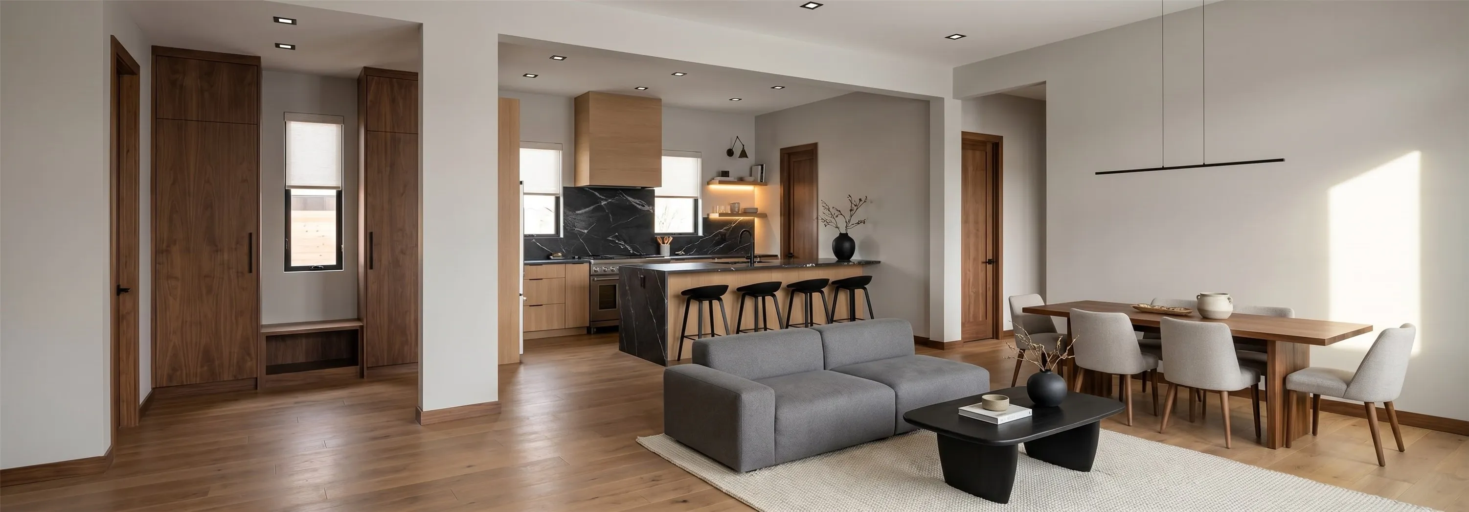 Open-concept living area with wood-finish flooring, recessed lighting, and a linear pendant light fixture