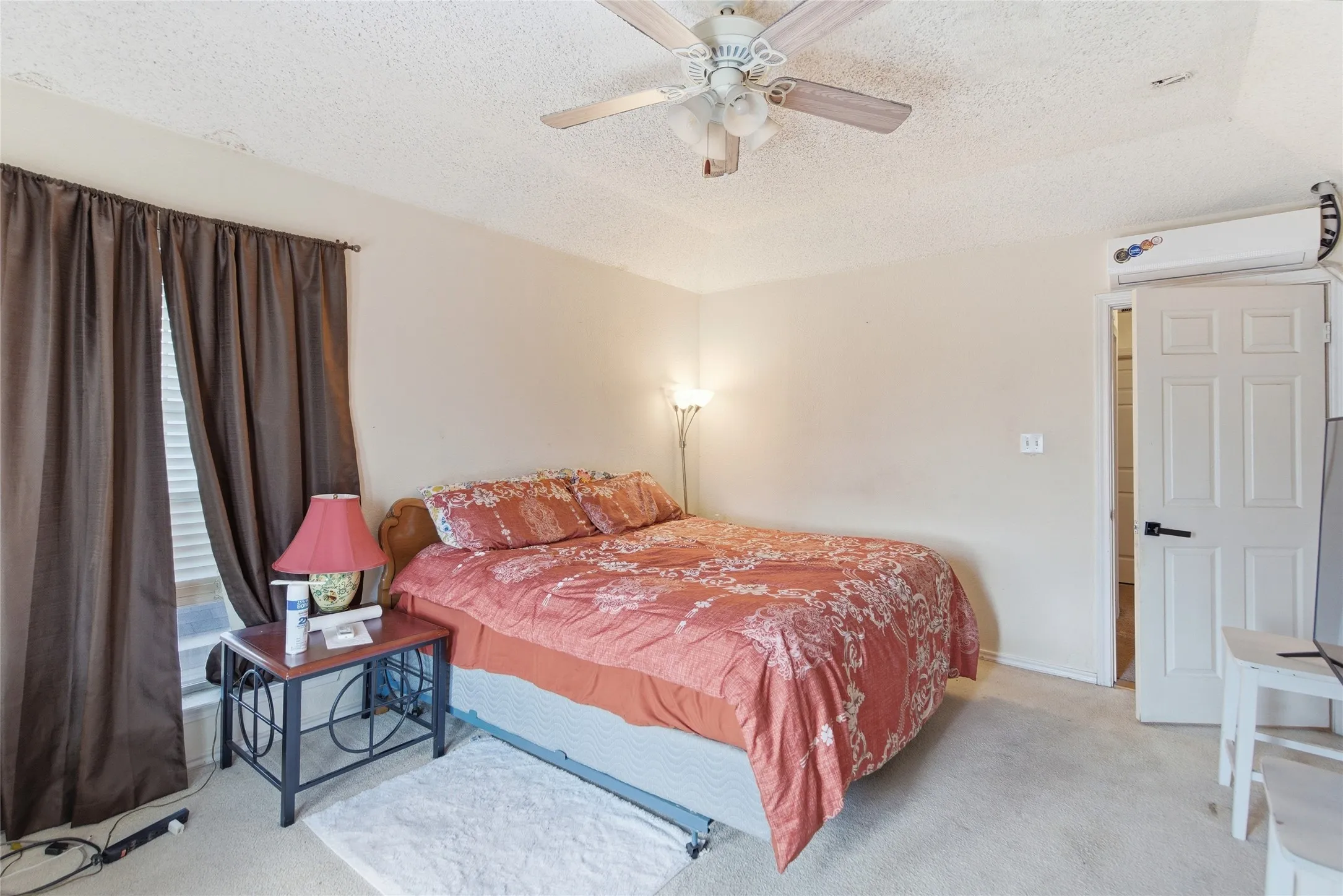 Carpeted room featuring a ceiling fan with integrated lighting, a window with blinds, and a built-in air conditioning unit