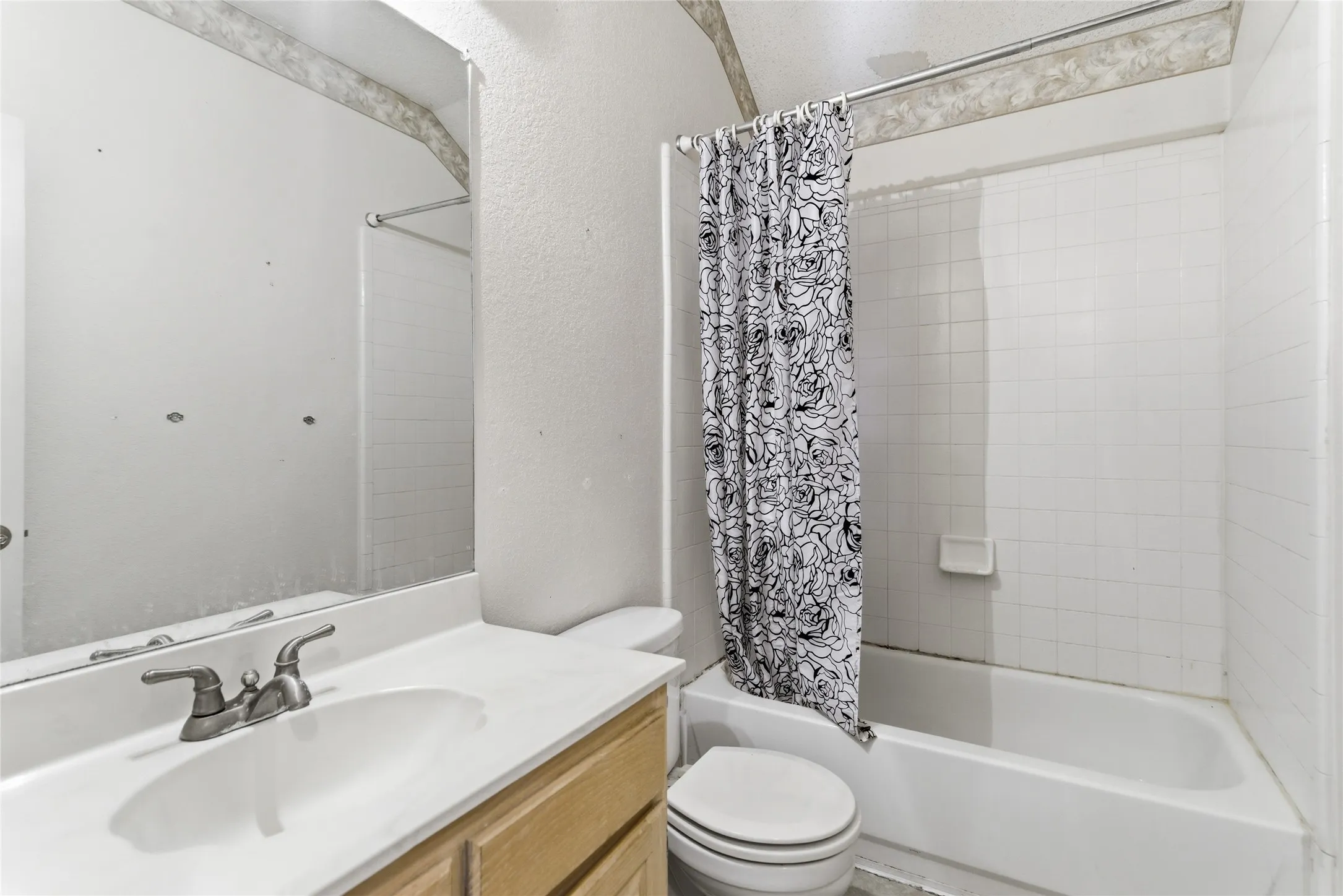 Full bathroom featuring a single vanity with wood-finish cabinetry, a white countertop, and a built-in sink