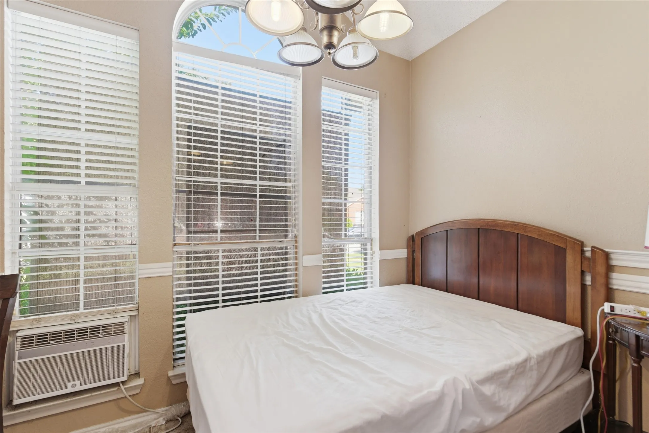 Room featuring neutral wall tones, a multipane arched window, and a five-light ceiling fixture