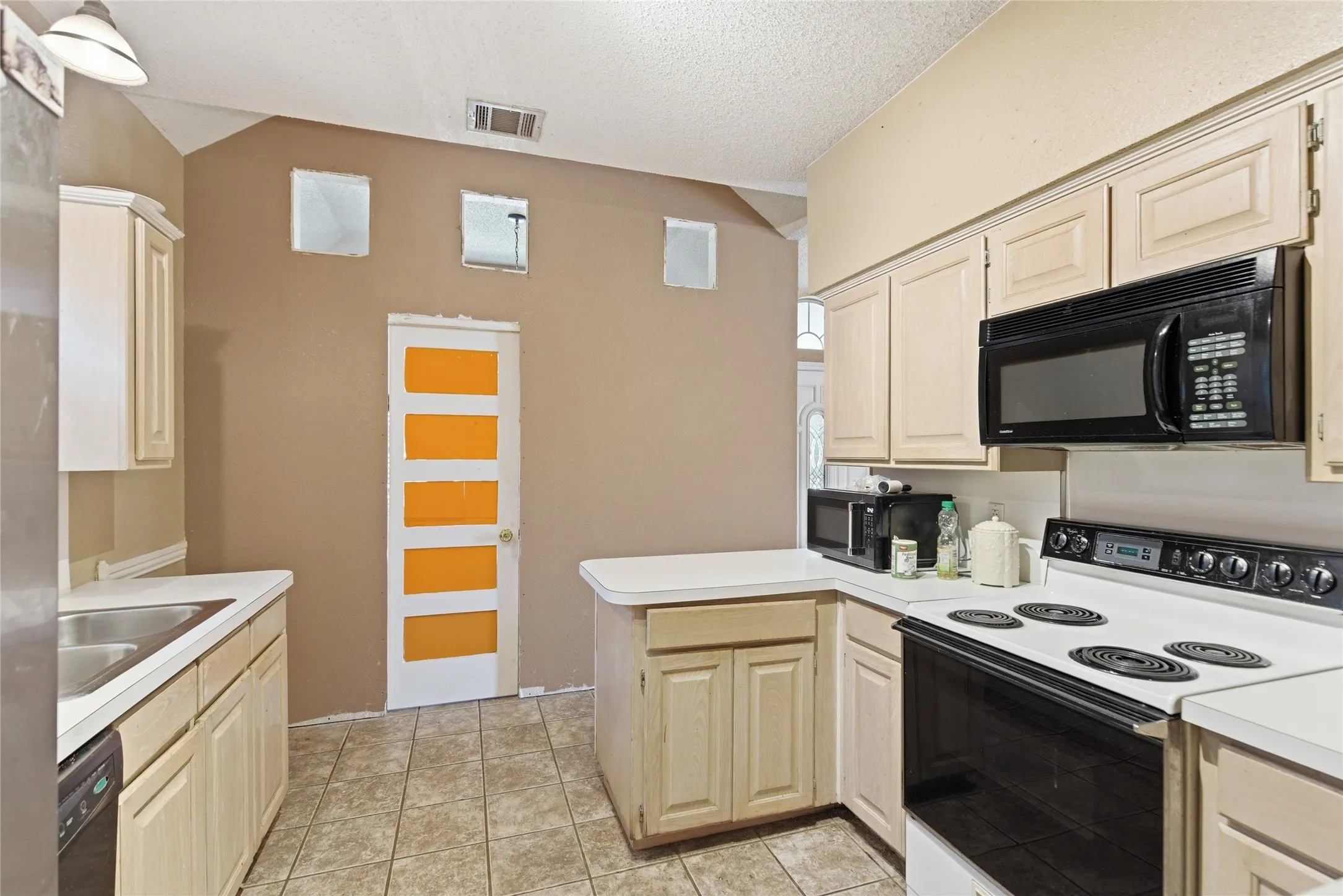 Kitchen featuring light-toned cabinetry, white countertops, and black built-in appliances