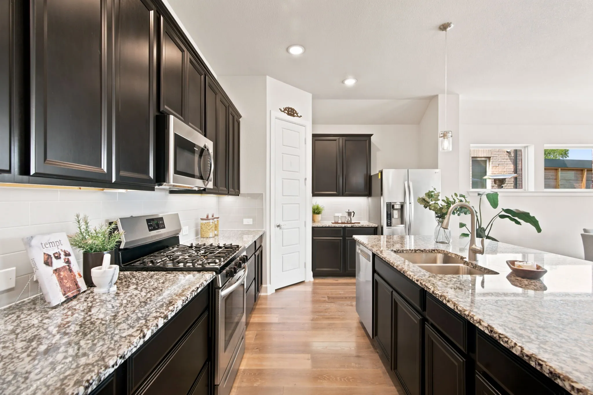 Gourmet kitchen featuring dark wood cabinetry, granite countertops, stainless steel appliances, a tile backsplash, and wood-finish flooring