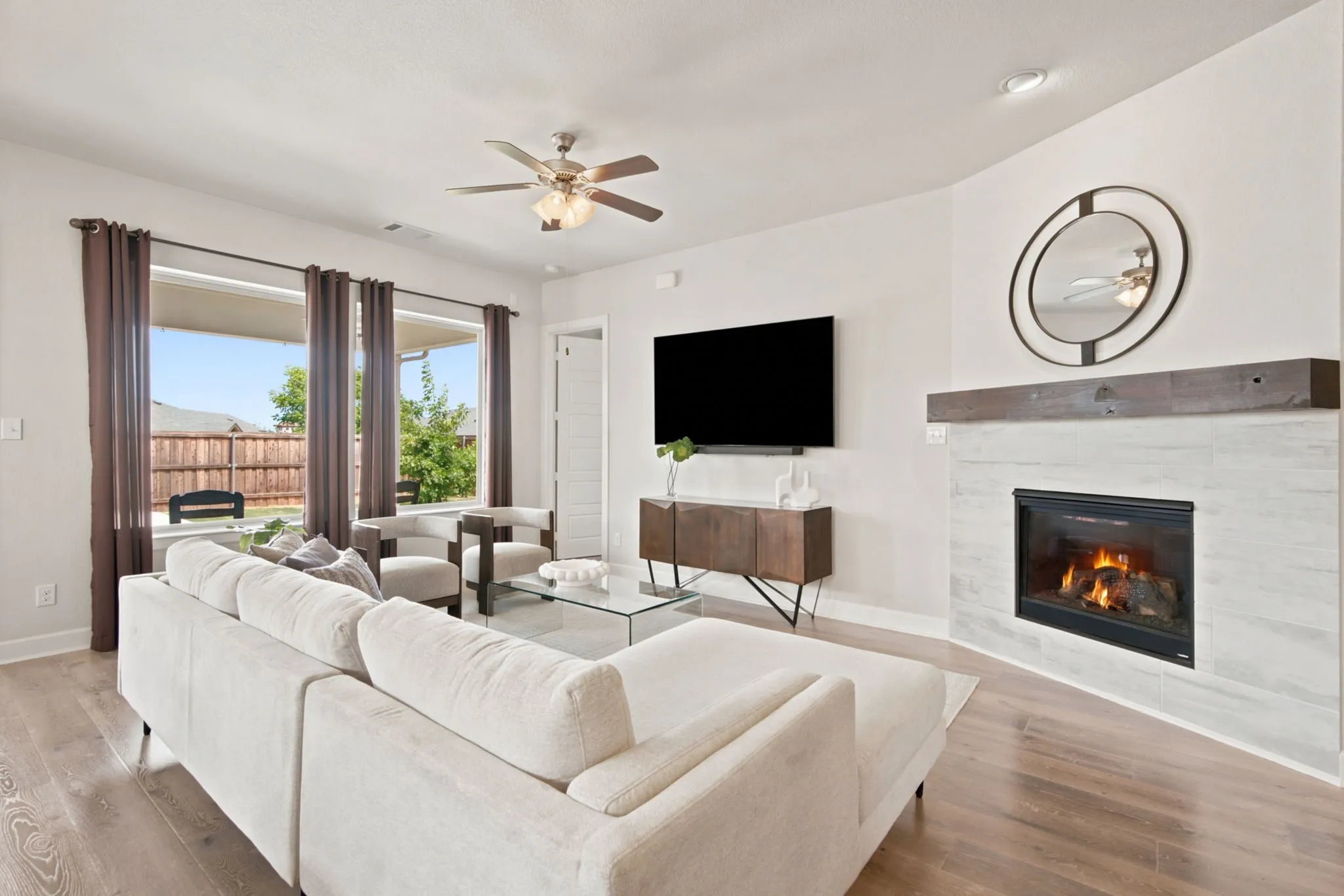 Wood-finish flooring throughout, multiple windows, built-in fireplace with tile surround, wood mantel, and recessed lighting