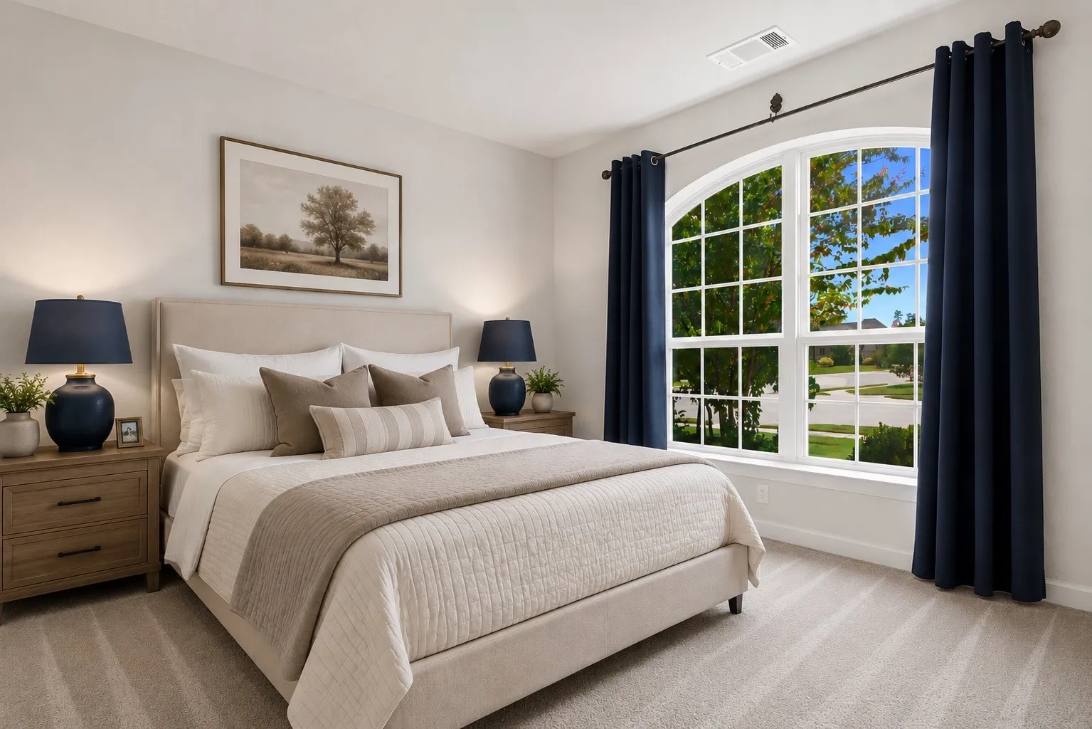 Front Bedroom featuring an arched window with grid details, light-toned carpeting, and a neutral wall color (virtually staged)