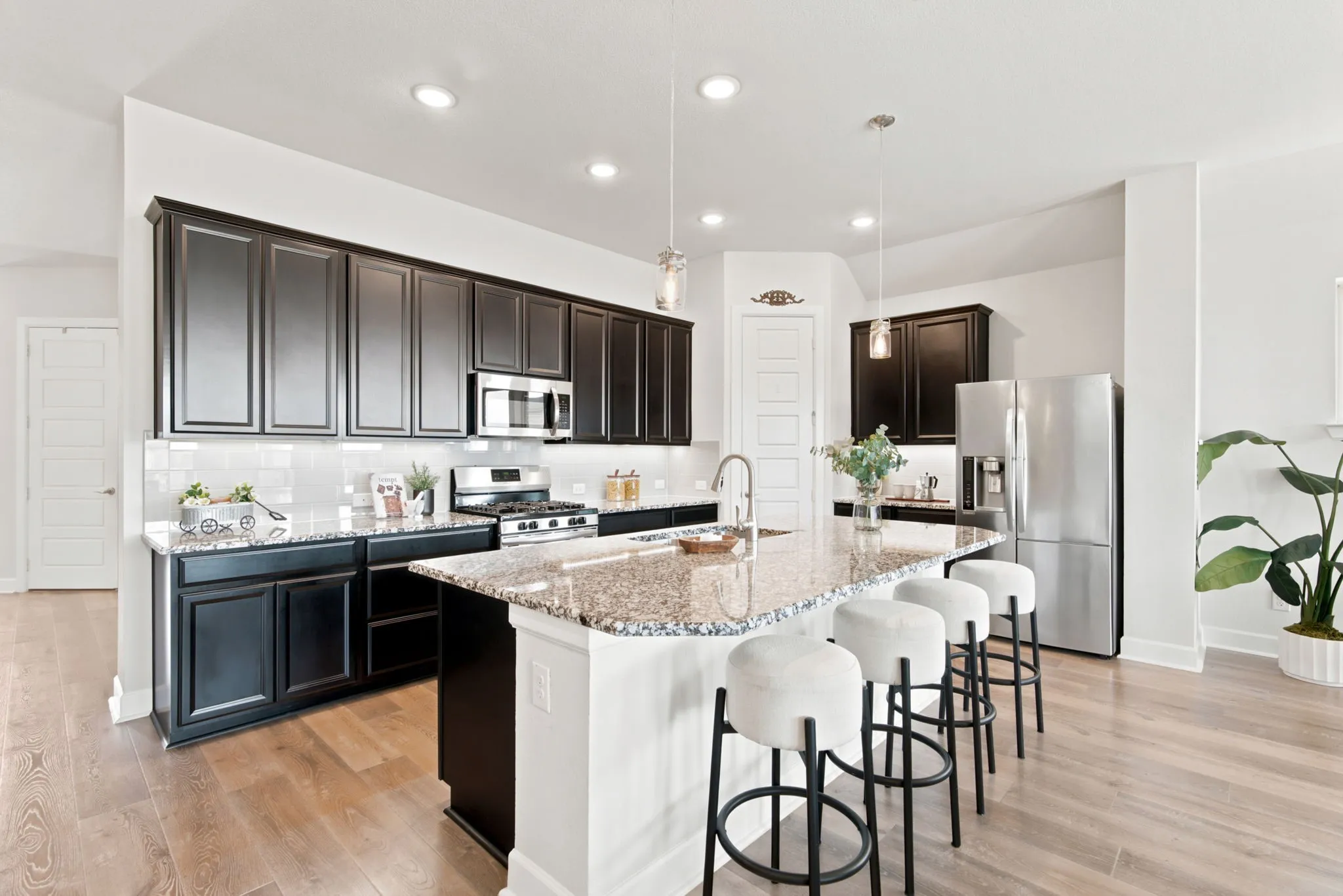 Spacious kitchen with a central island, dark wood-finish cabinetry, stainless steel appliances, and wood-finish flooring