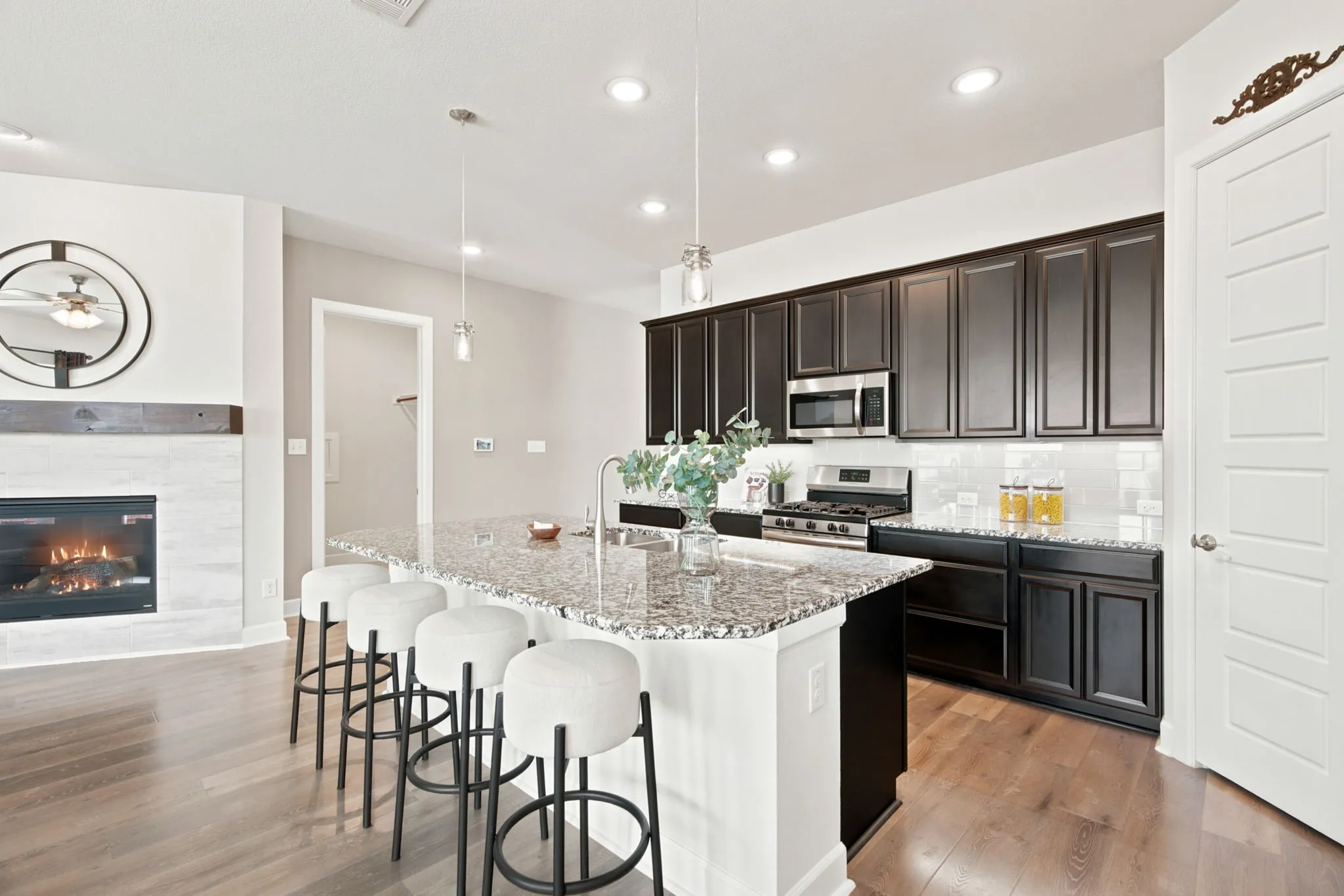 Wood-finish flooring throughout, featuring a kitchen with dark cabinetry, stainless steel appliances, and a central island with a sink