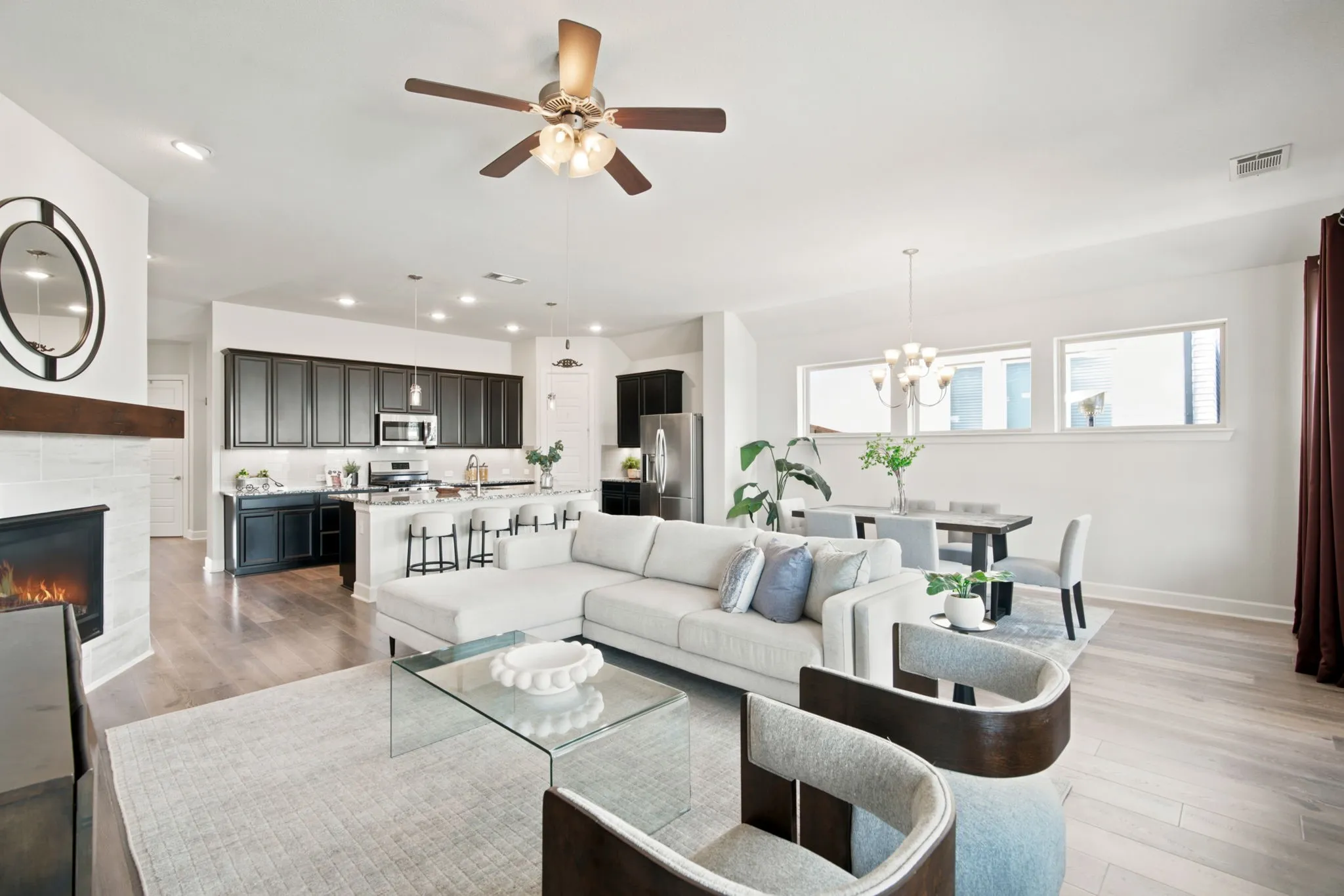 Open-concept living space featuring a light-filled great room with recessed lighting and ceiling fan, complemented by a neutral color palette and wood-finish flooring throughout