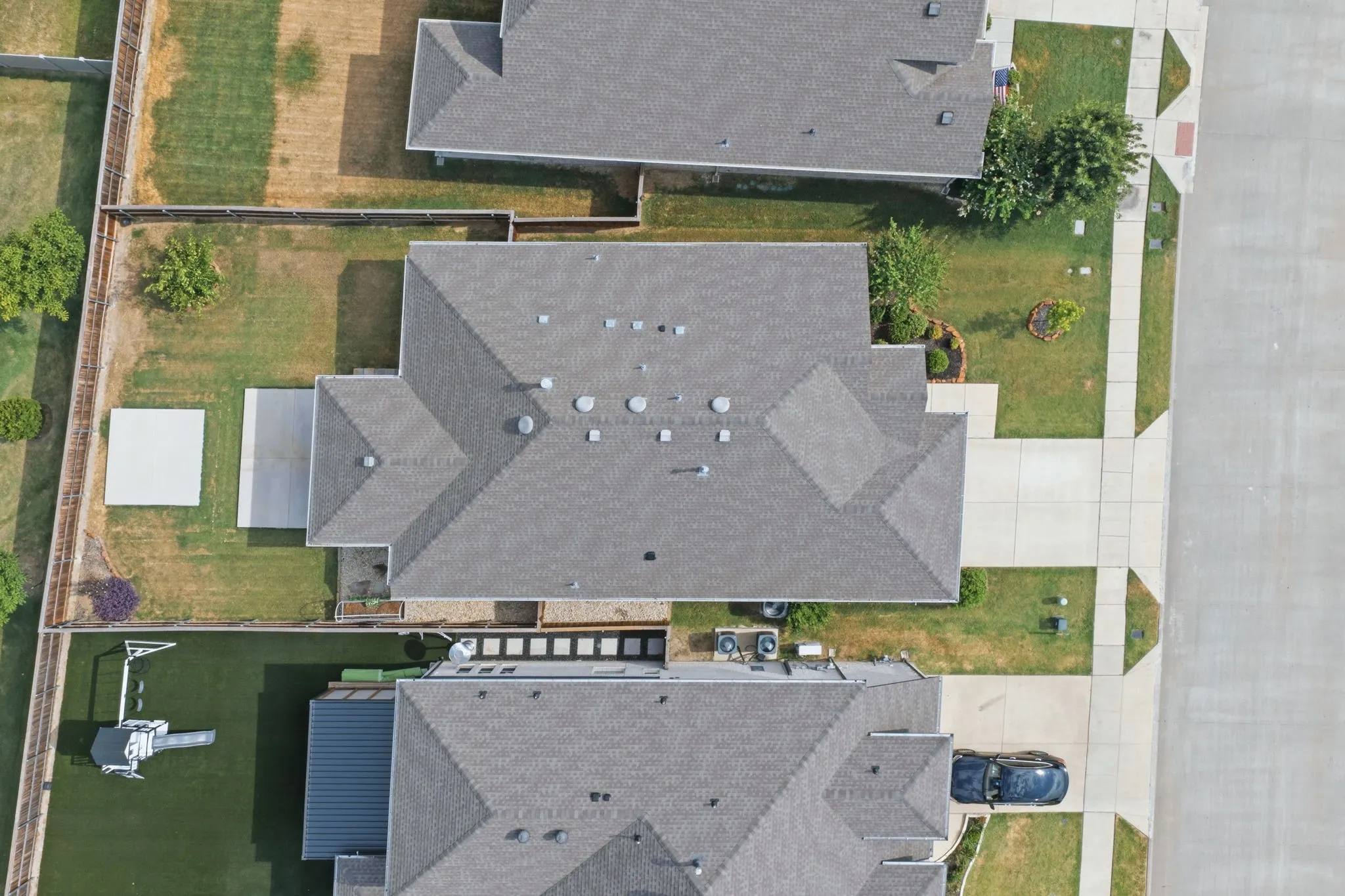 Gable roofline residential property featuring a paved driveway, concrete patio, and a grassed backyard