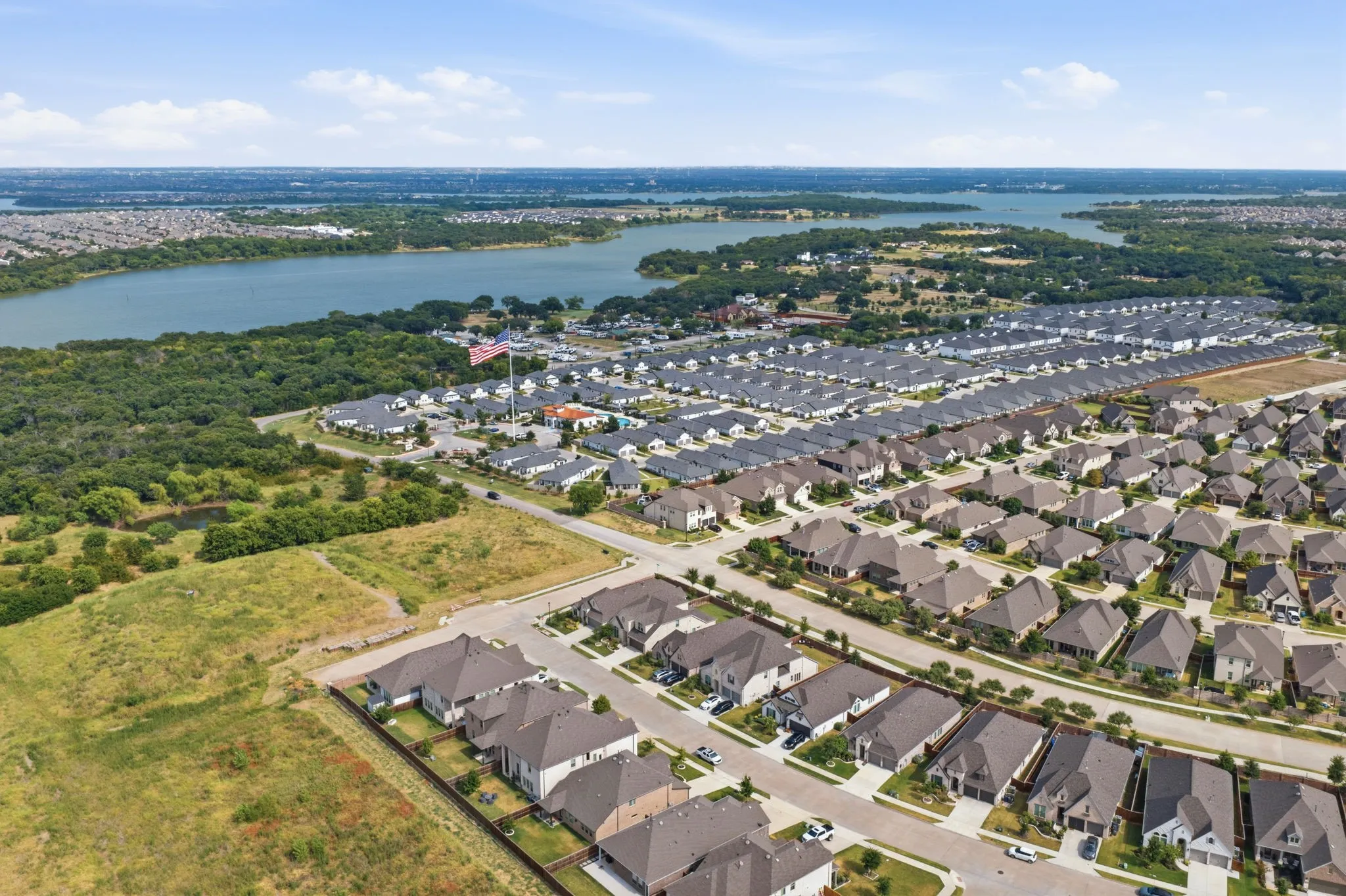 Expansive aerial capturing a residential community with a large body of water in the background