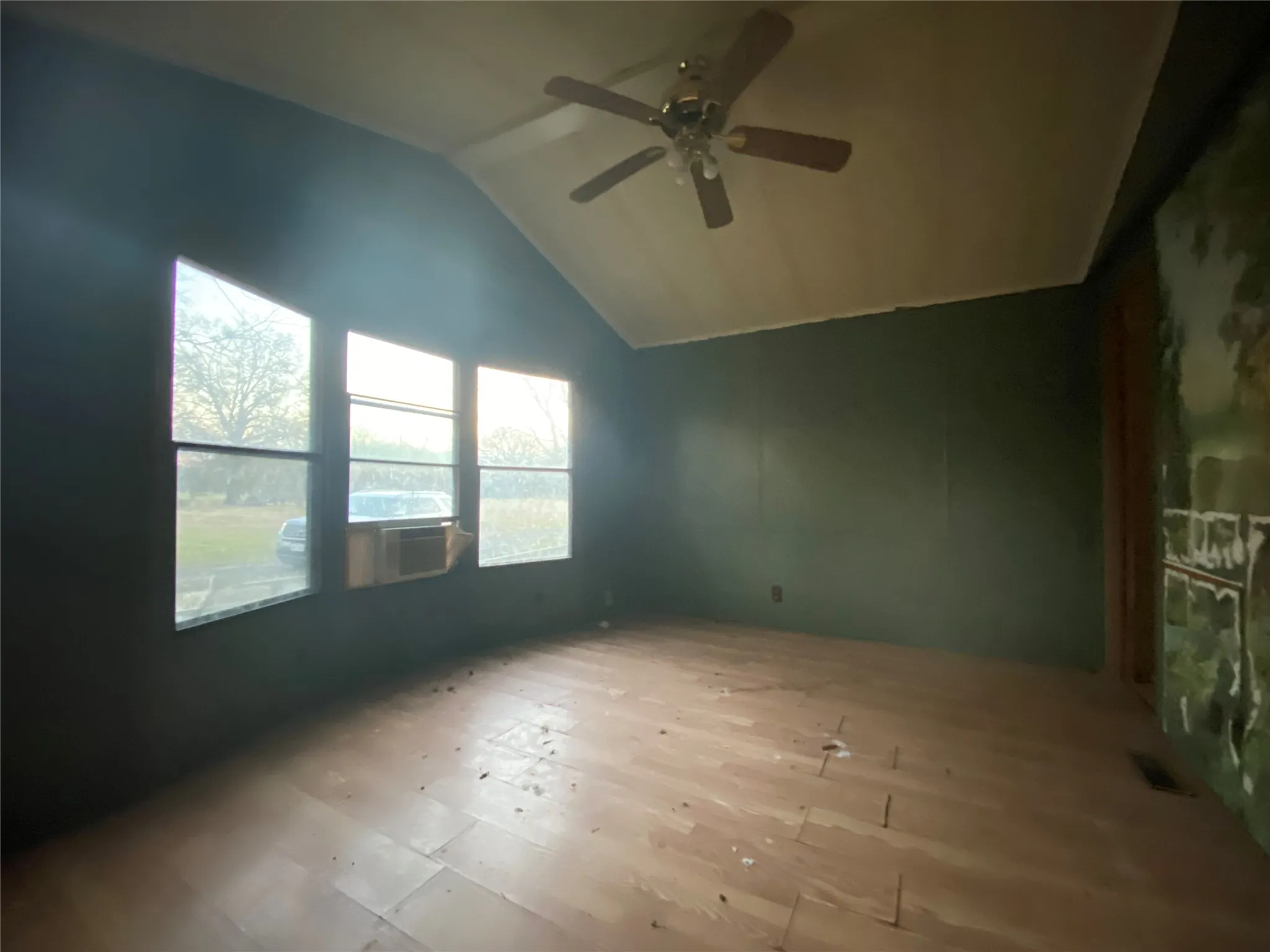 Spare room featuring ceiling fan, lofted ceiling, and light hardwood / wood-style flooring