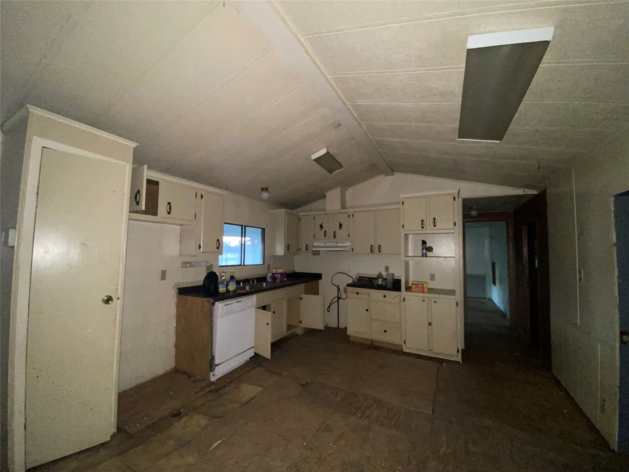 Kitchen featuring dishwasher, white cabinets, and lofted ceiling