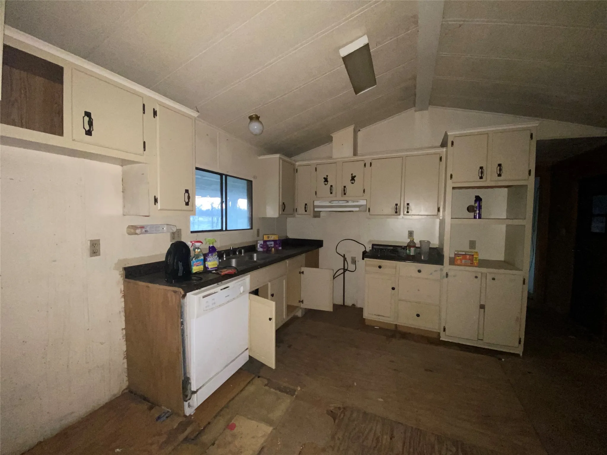 Kitchen with cream cabinetry, dishwasher, lofted ceiling, and sink