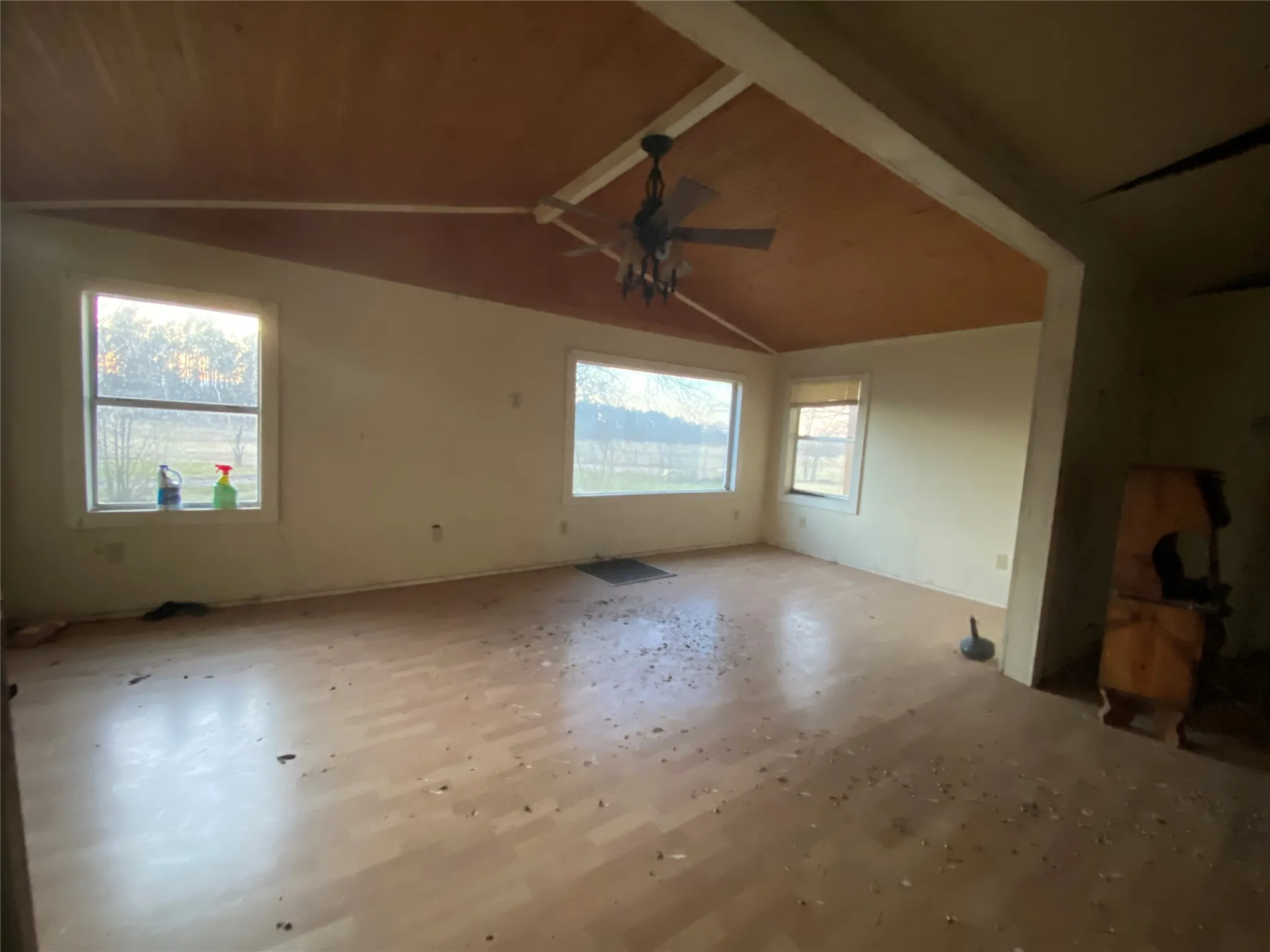 Unfurnished room with lofted ceiling with beams and ceiling fan