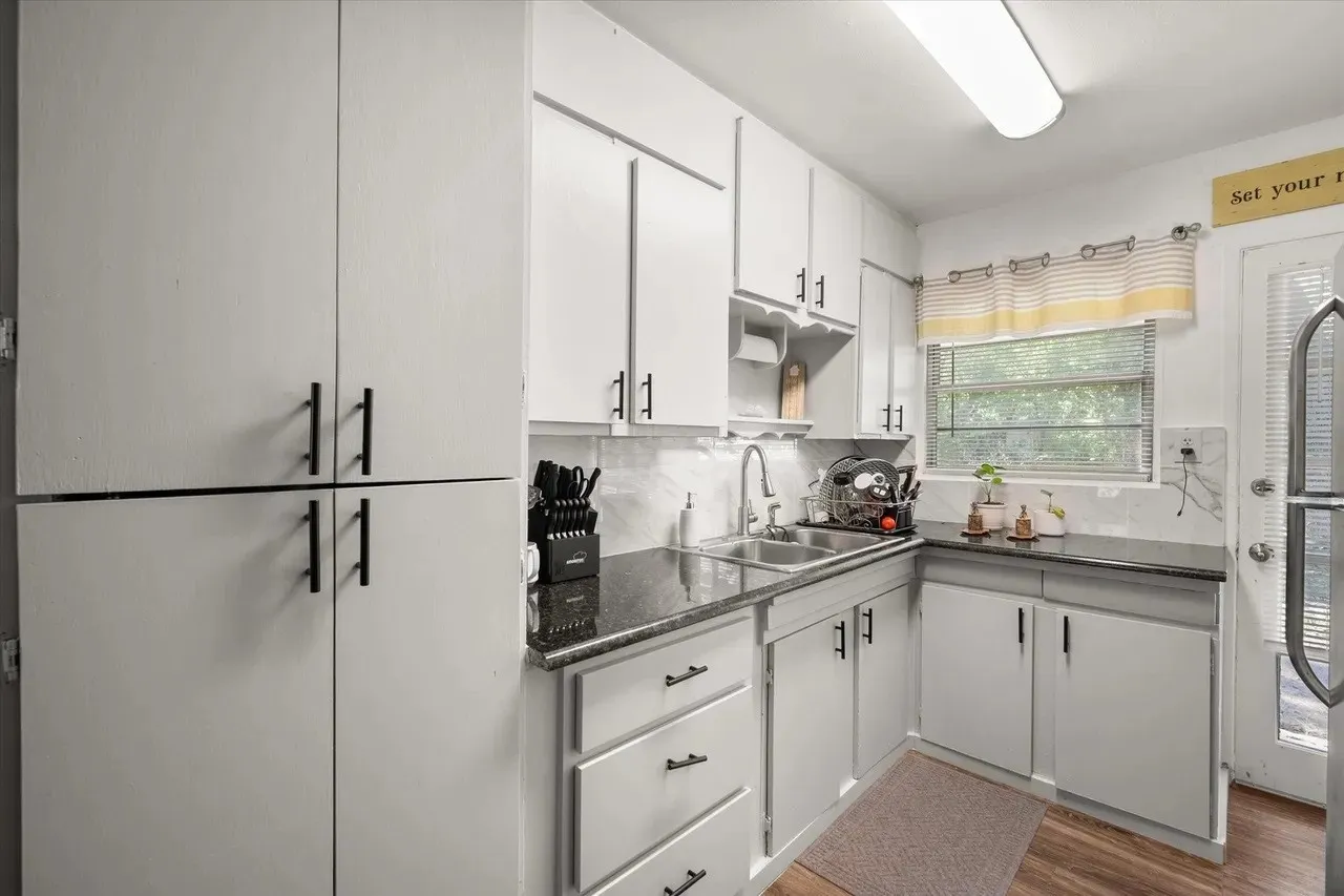 Kitchen featuring white cabinetry and dark countertops