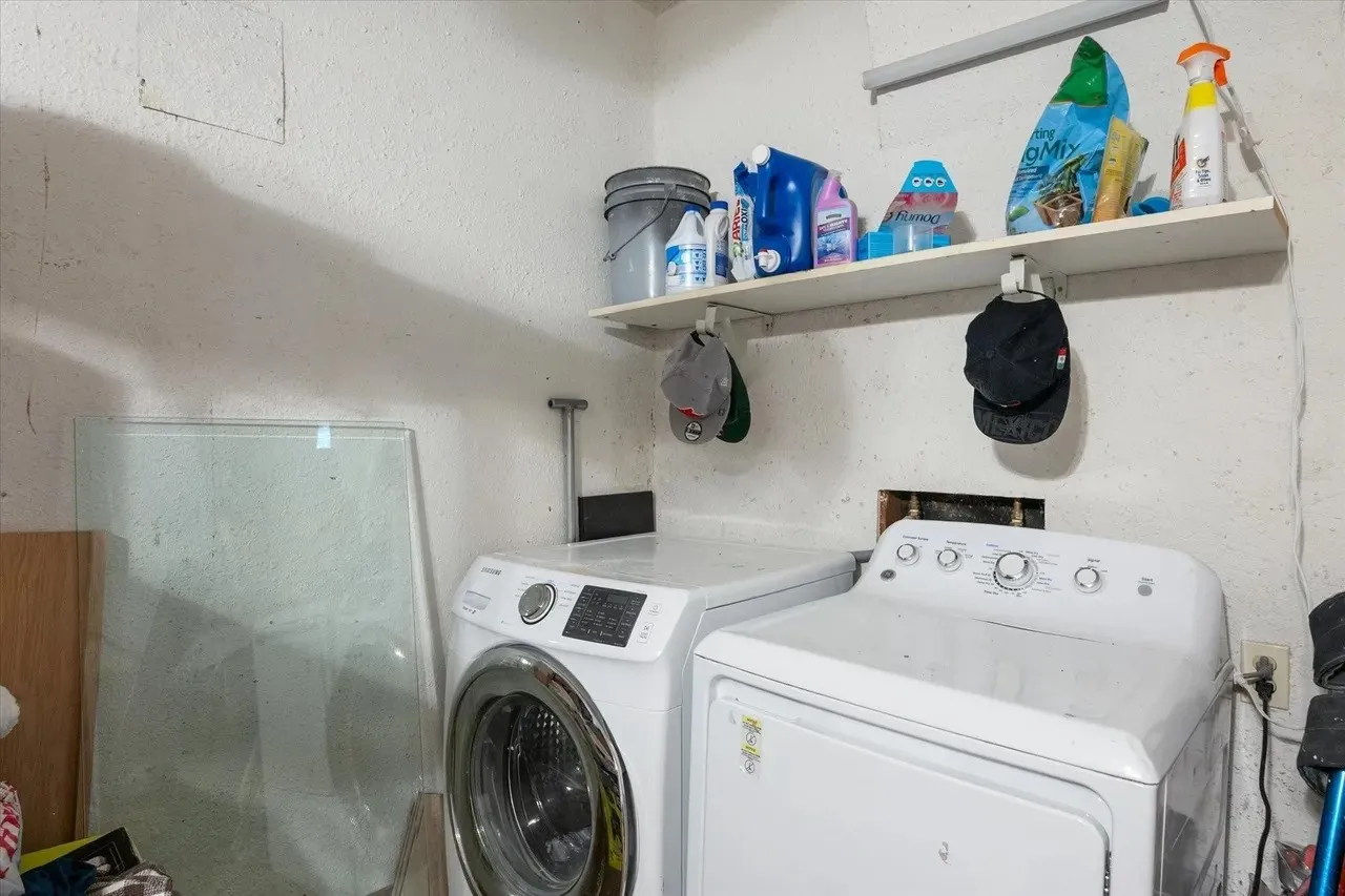 Utility area with hookups for washer and dryer, featuring white appliances and an overhead storage shelf
