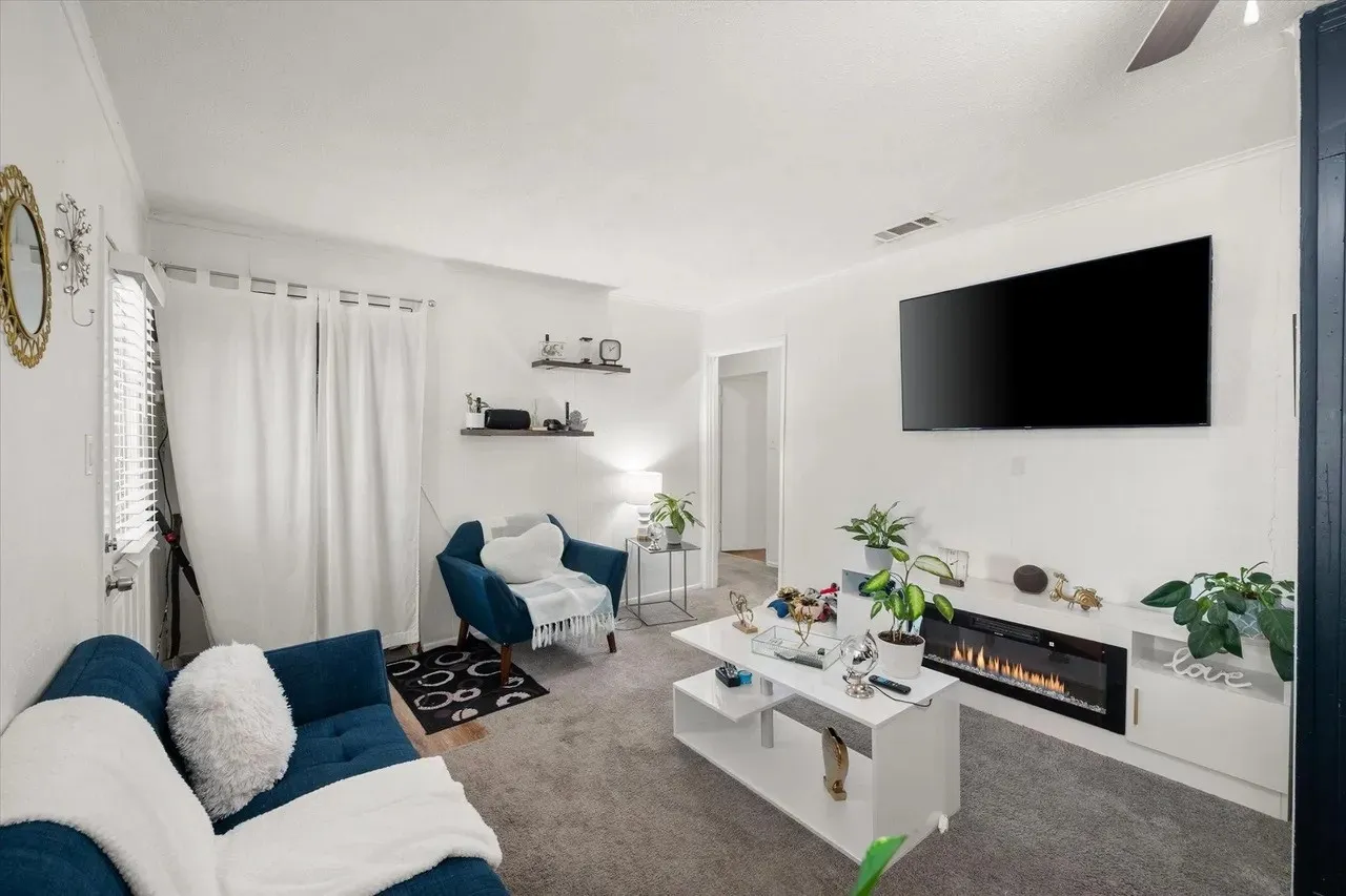 Living area featuring wall-mounted television, built-in electric fireplace, recessed lighting, and carpeted flooring