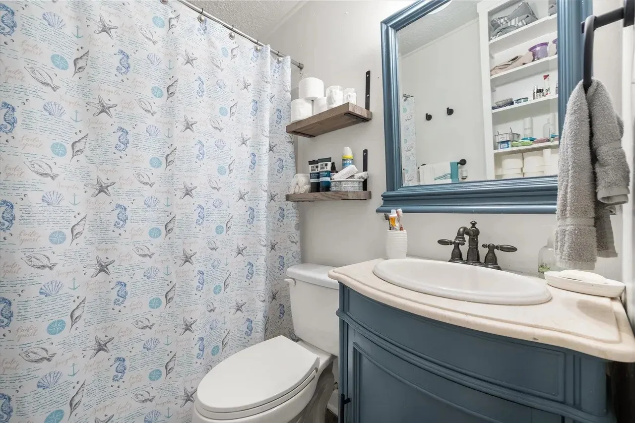 Bathroom featuring a blue framed mirror, a blue vanity with an integrated sink, and an oil-rubbed bronze faucet