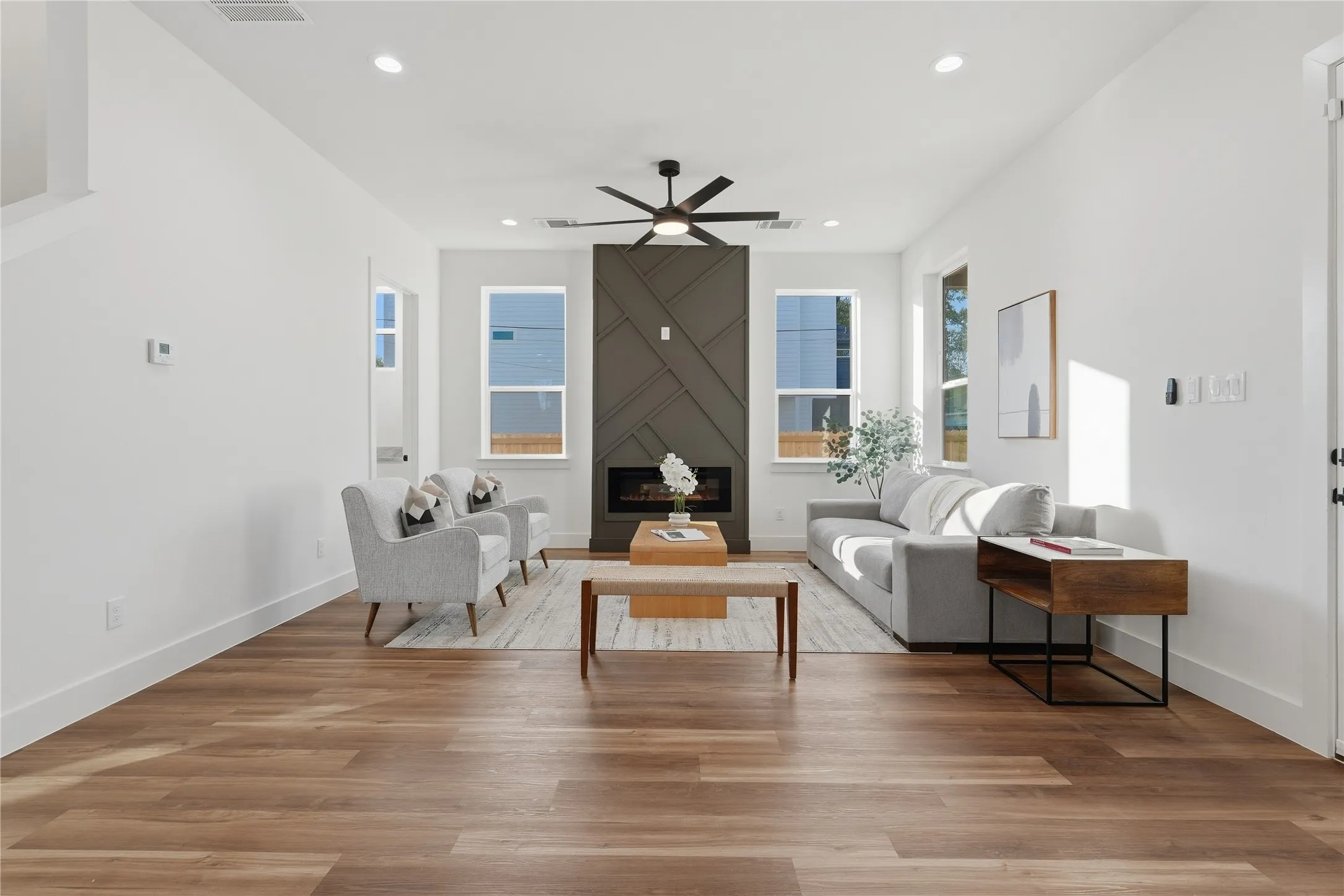 Spacious living area featuring wood-finish flooring, recessed lighting, and a modern fireplace with a geometric surround