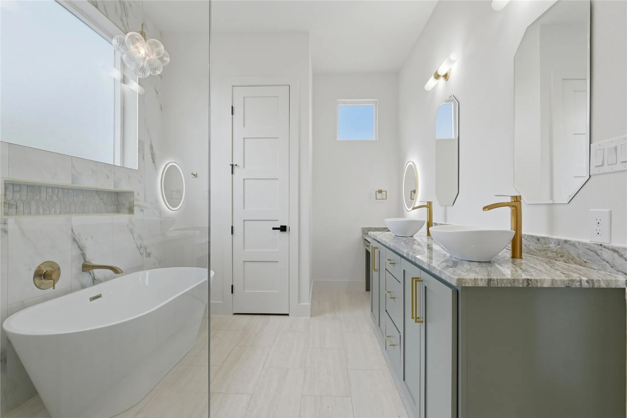 Contemporary bathroom featuring a freestanding tub, a dual vanity with vessel sinks, gold-finish fixtures, and a large format tile shower surround