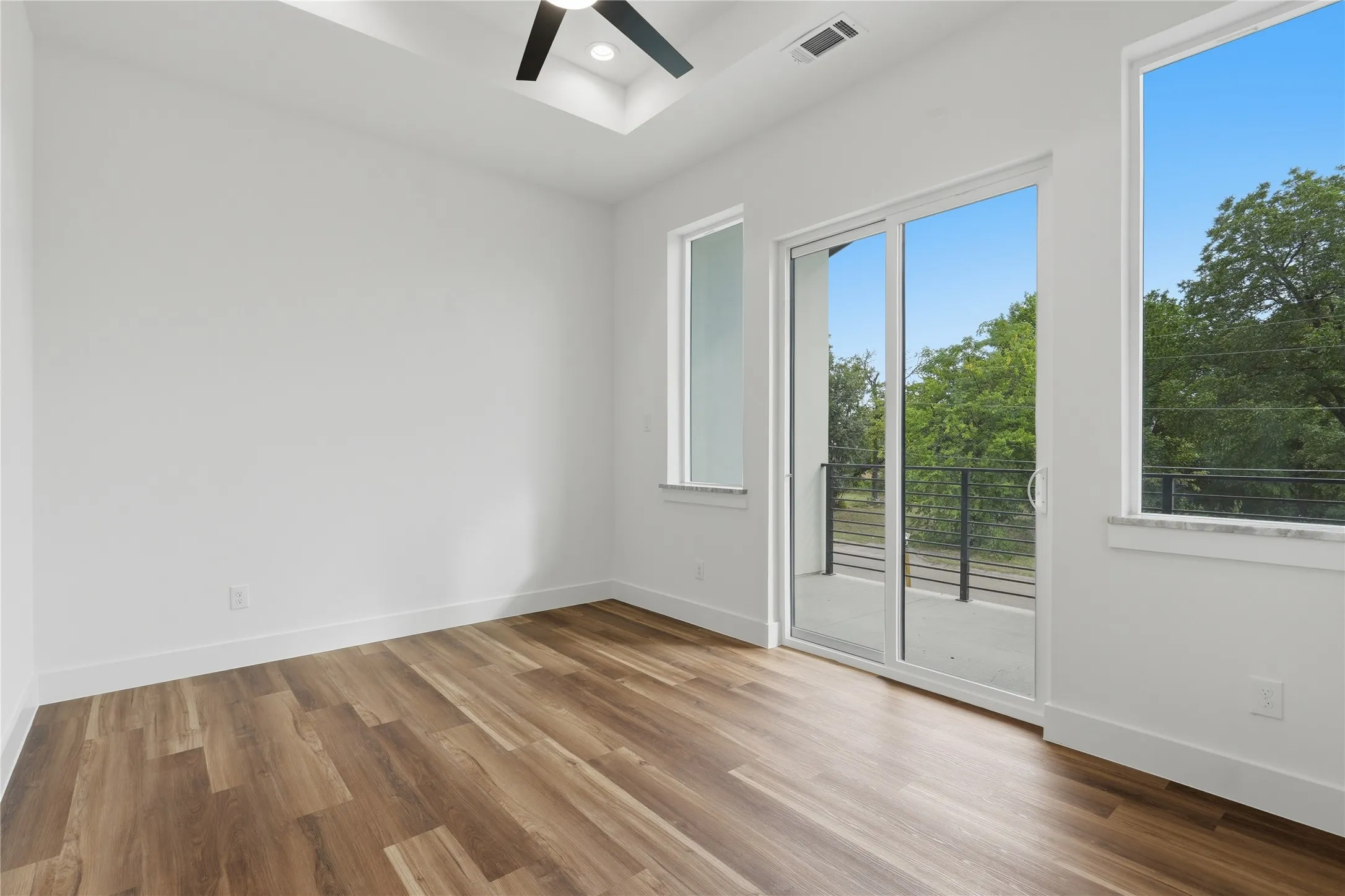 Wood-finish flooring, white walls, and a contemporary ceiling fan