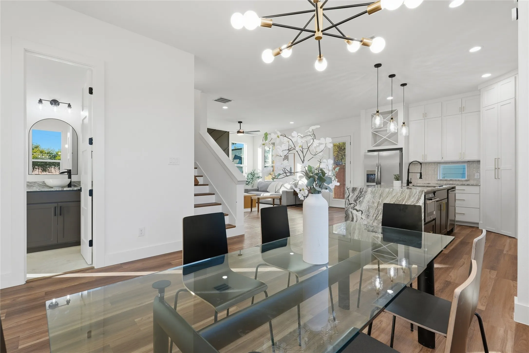 Wood-finish flooring throughout, bright white walls, and a contemporary chandelier