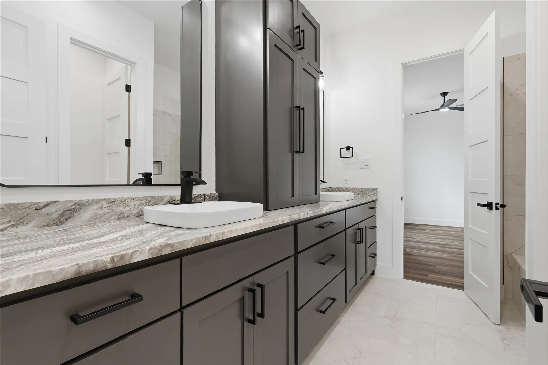 Dual vanity featuring gray cabinetry with matte black hardware, stone-finish countertops, and rectangular vessel sinks with matte black faucets