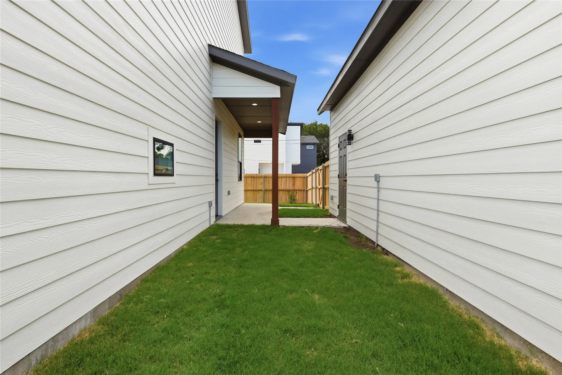 Manicured green lawn separating two structures with white horizontal siding