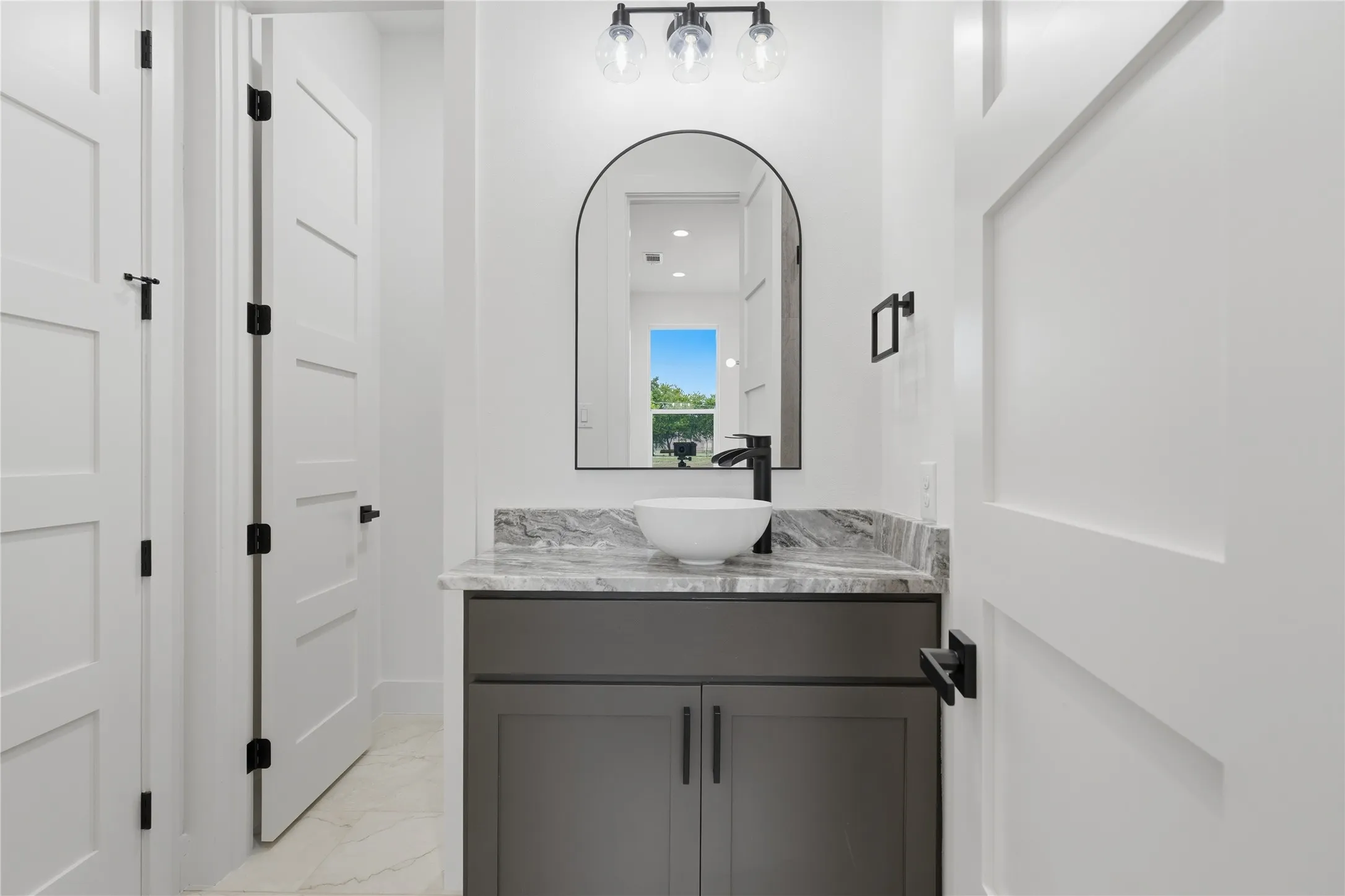 Modern vanity with a vessel sink, dark cabinetry, and a stone countertop