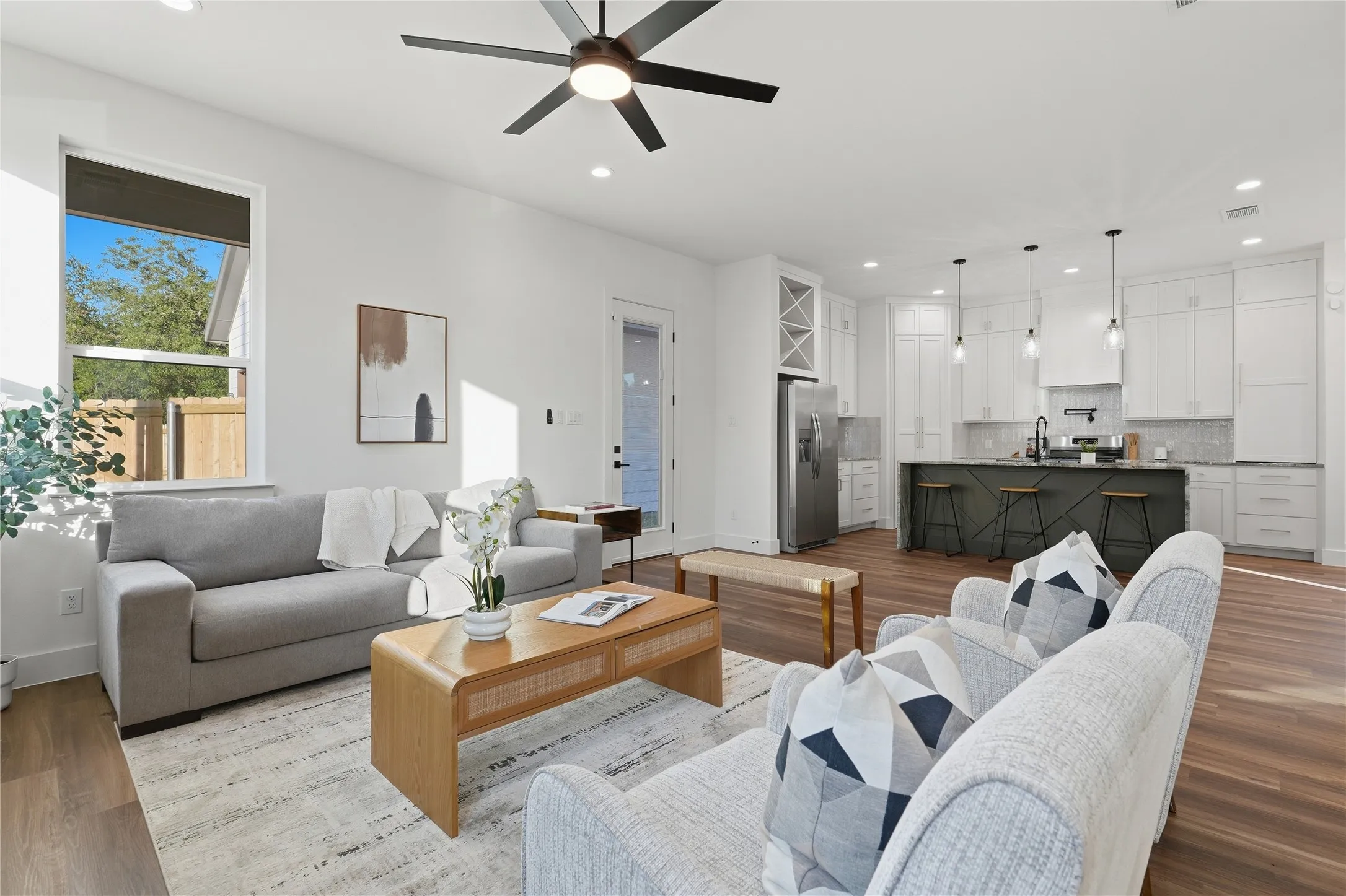 Open-concept living area with wood-finish flooring, white walls, and a contemporary ceiling fan