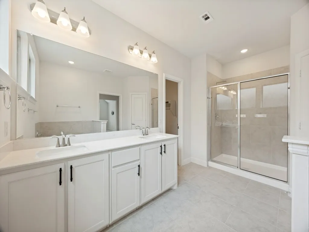 Bathroom featuring a dual vanity with white cabinetry, light-toned countertops, and brushed nickel faucets