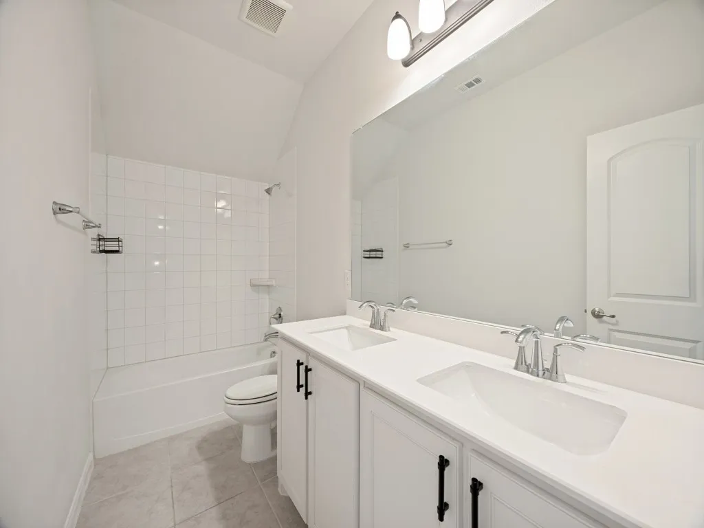 Bathroom featuring a white dual vanity with undermount sinks, chrome fixtures, and a large wall-mounted mirror