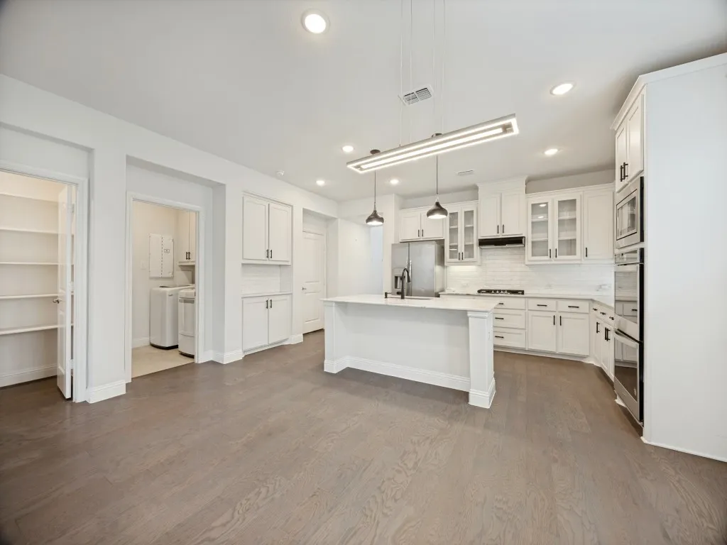 Open-concept kitchen with white cabinetry, stainless steel appliances, and a central island