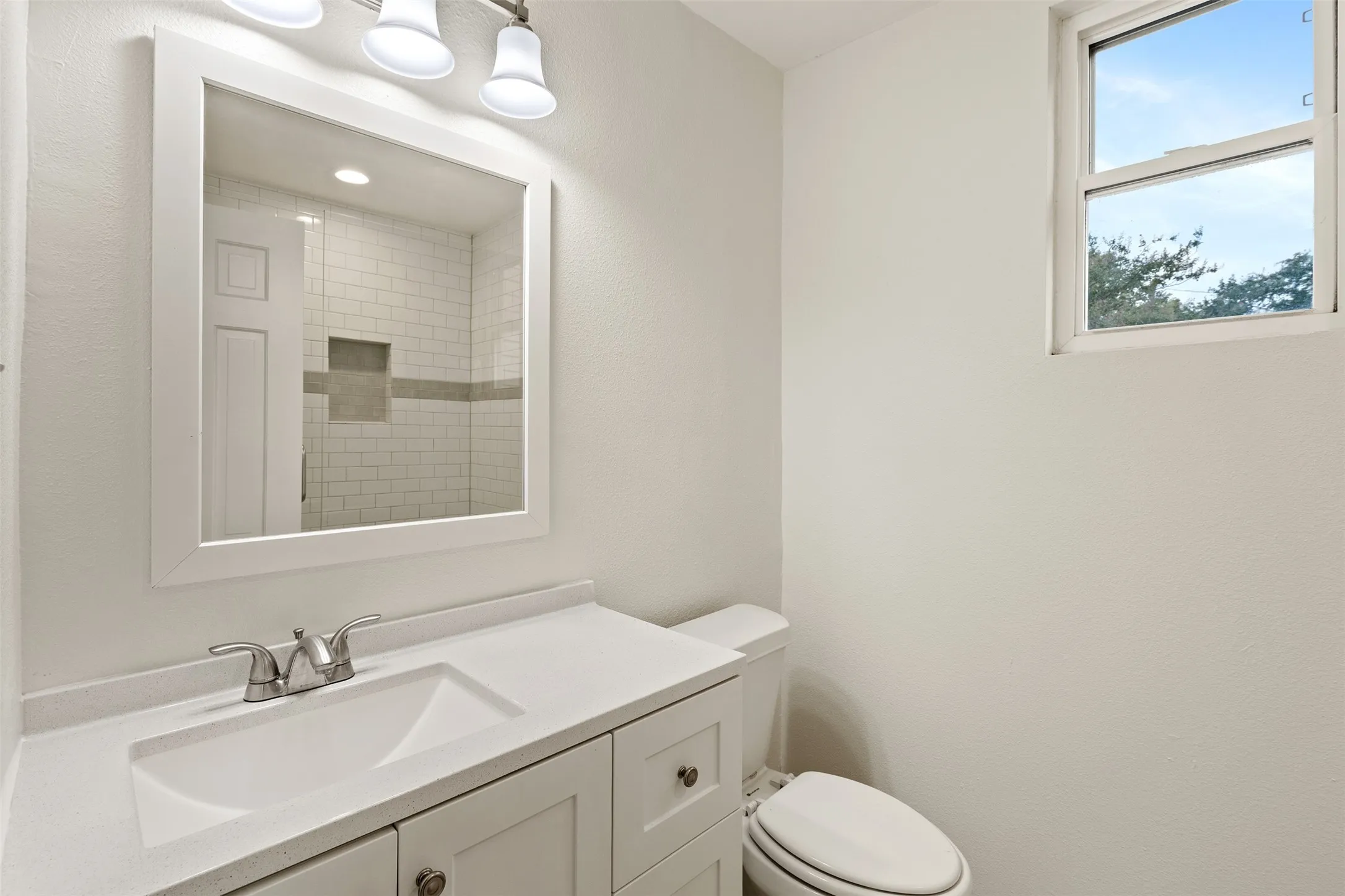 White vanity with integrated sink, brushed nickel faucet, and a framed mirror