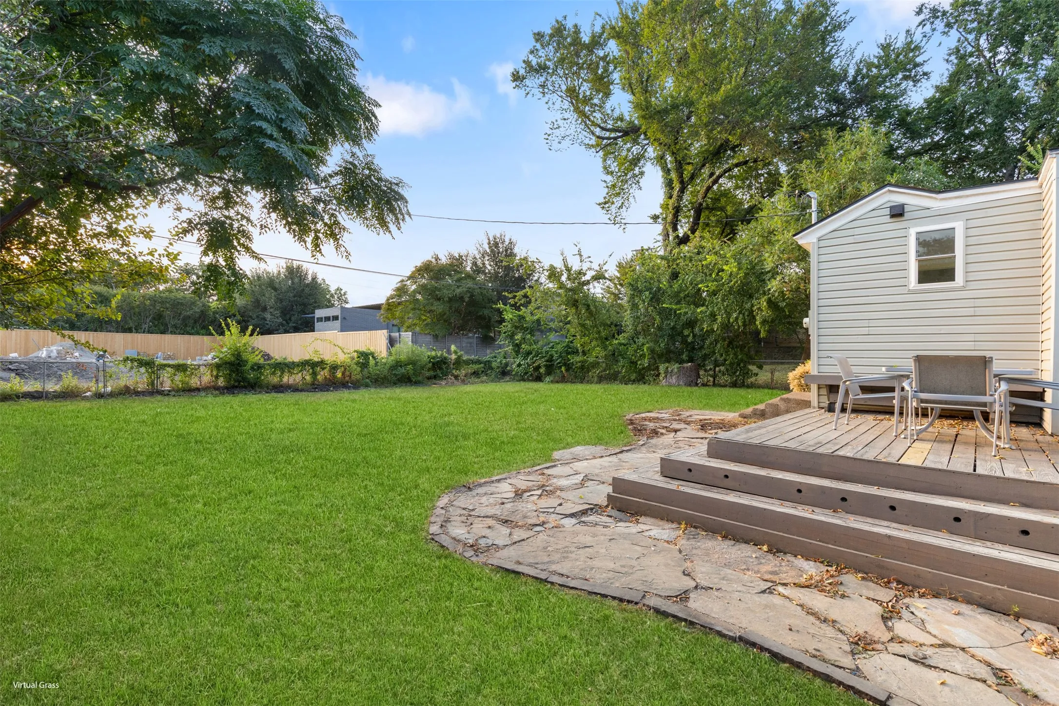 Expansive green lawn, multi-level wood deck, flagstone patio, and siding exterior