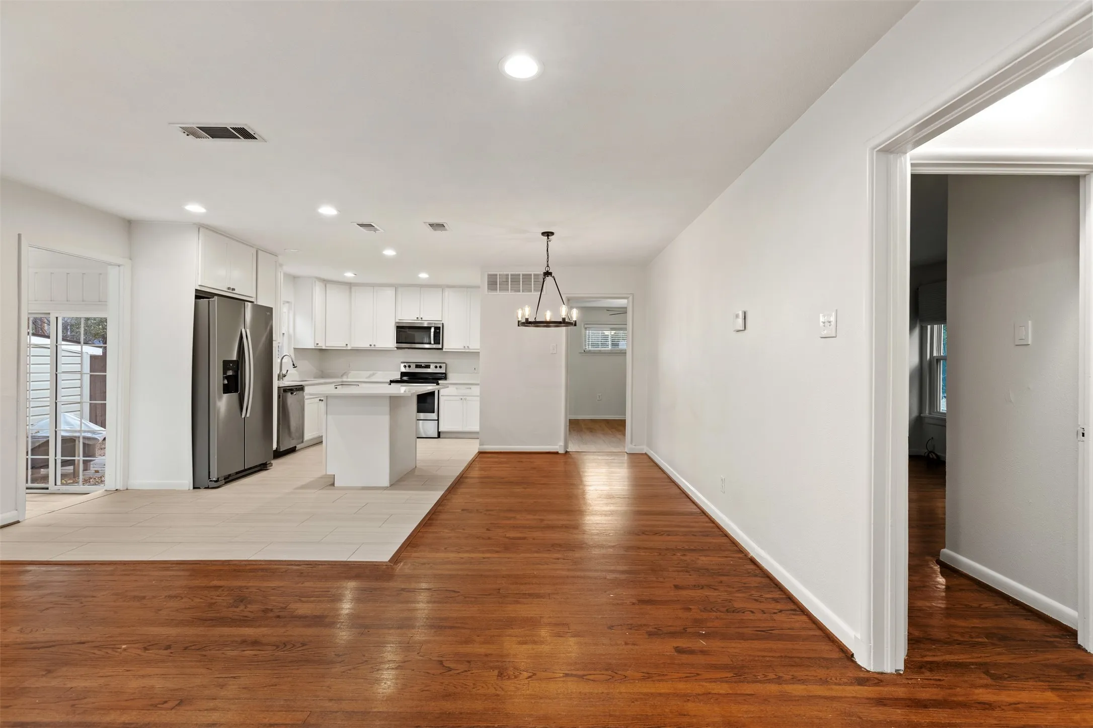 Hardwood flooring, recessed lighting, white cabinetry, stainless steel appliances, and a central island
