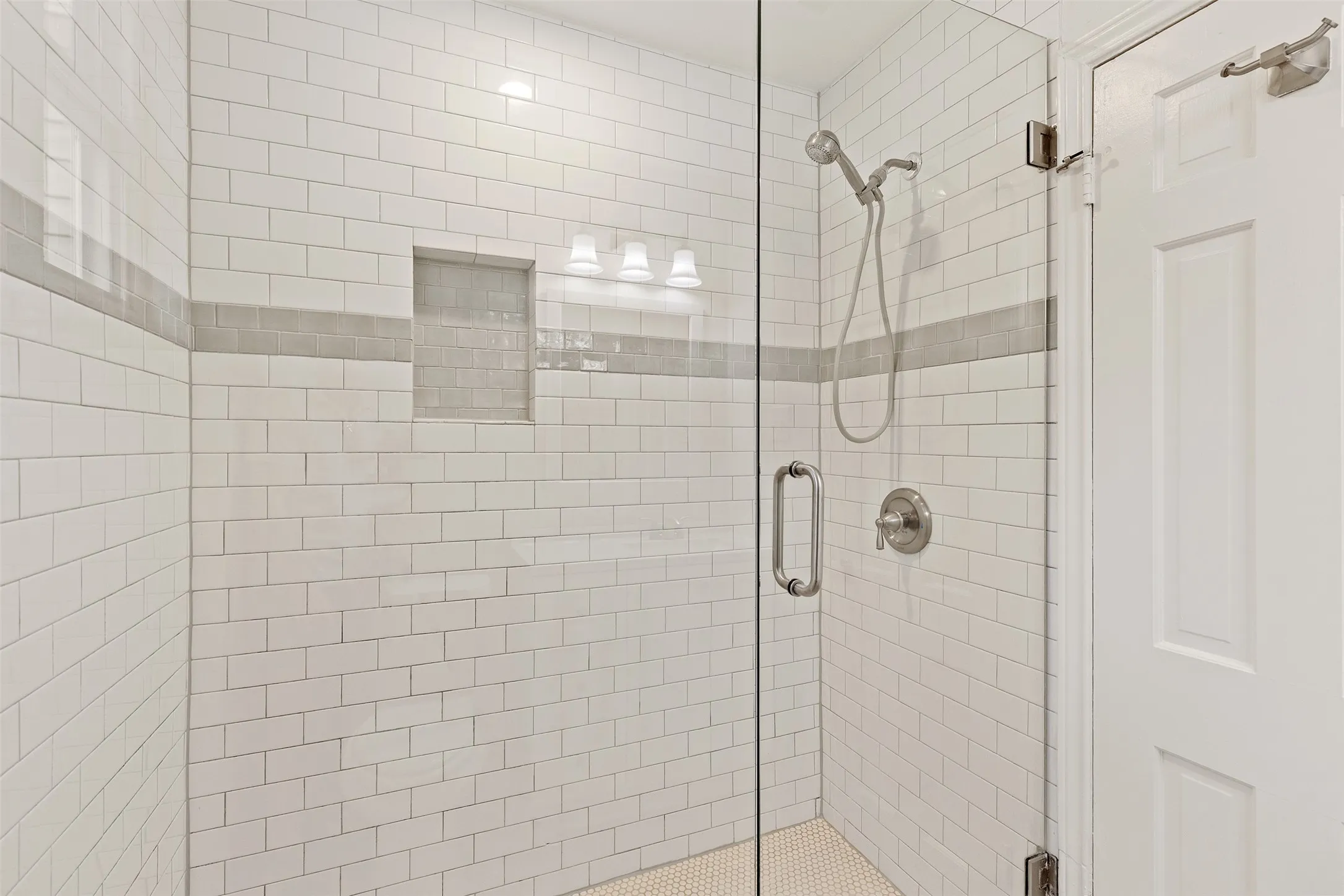 Glass-enclosed shower with subway tile surround, recessed niche, and brushed nickel fixtures