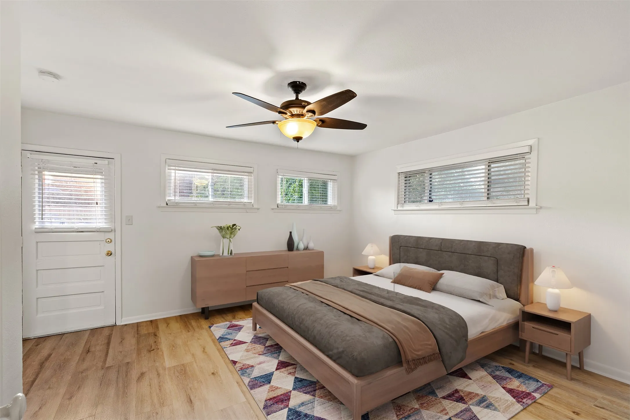 Wood-finish flooring throughout, white walls, and a ceiling fan with integrated lighting