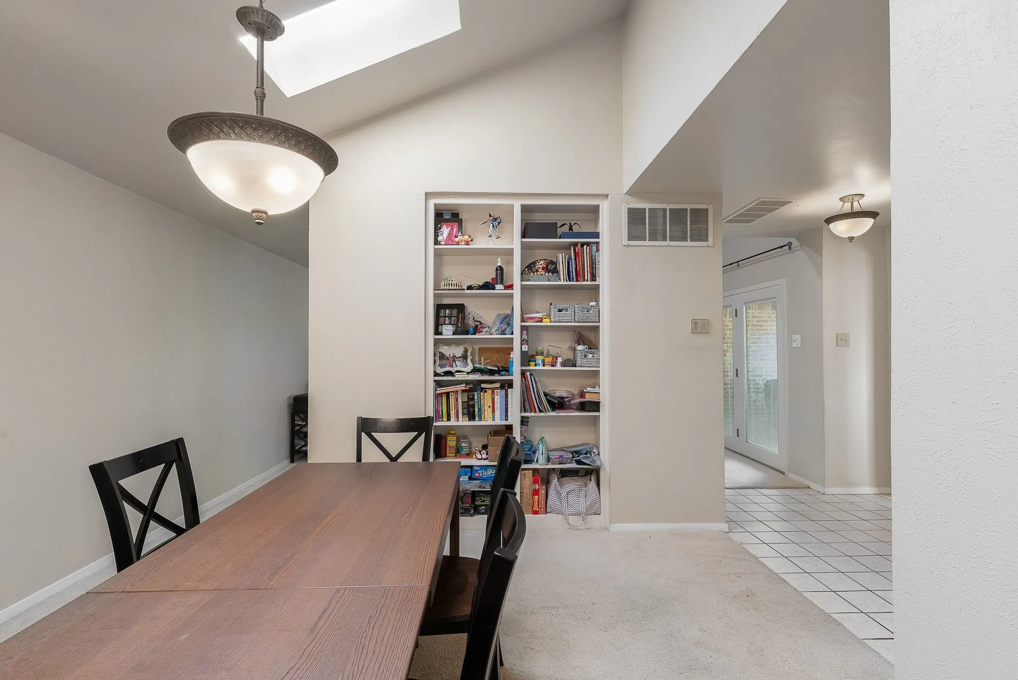 Naturally lit dining space, pendant lighting, skylight, built-in shelving.