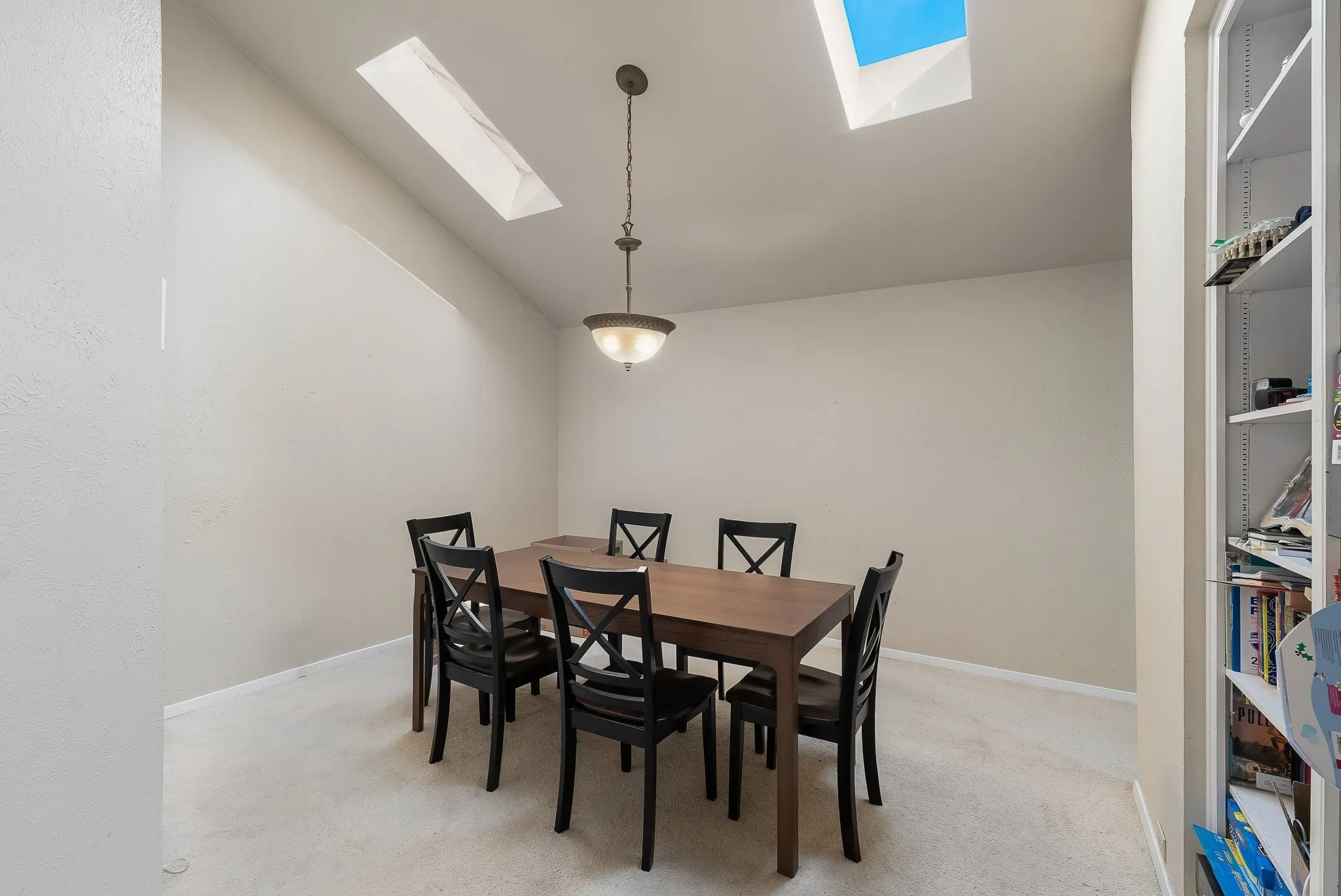 Naturally lit dining space, pendant. lighting, skylight, built-in shelving
