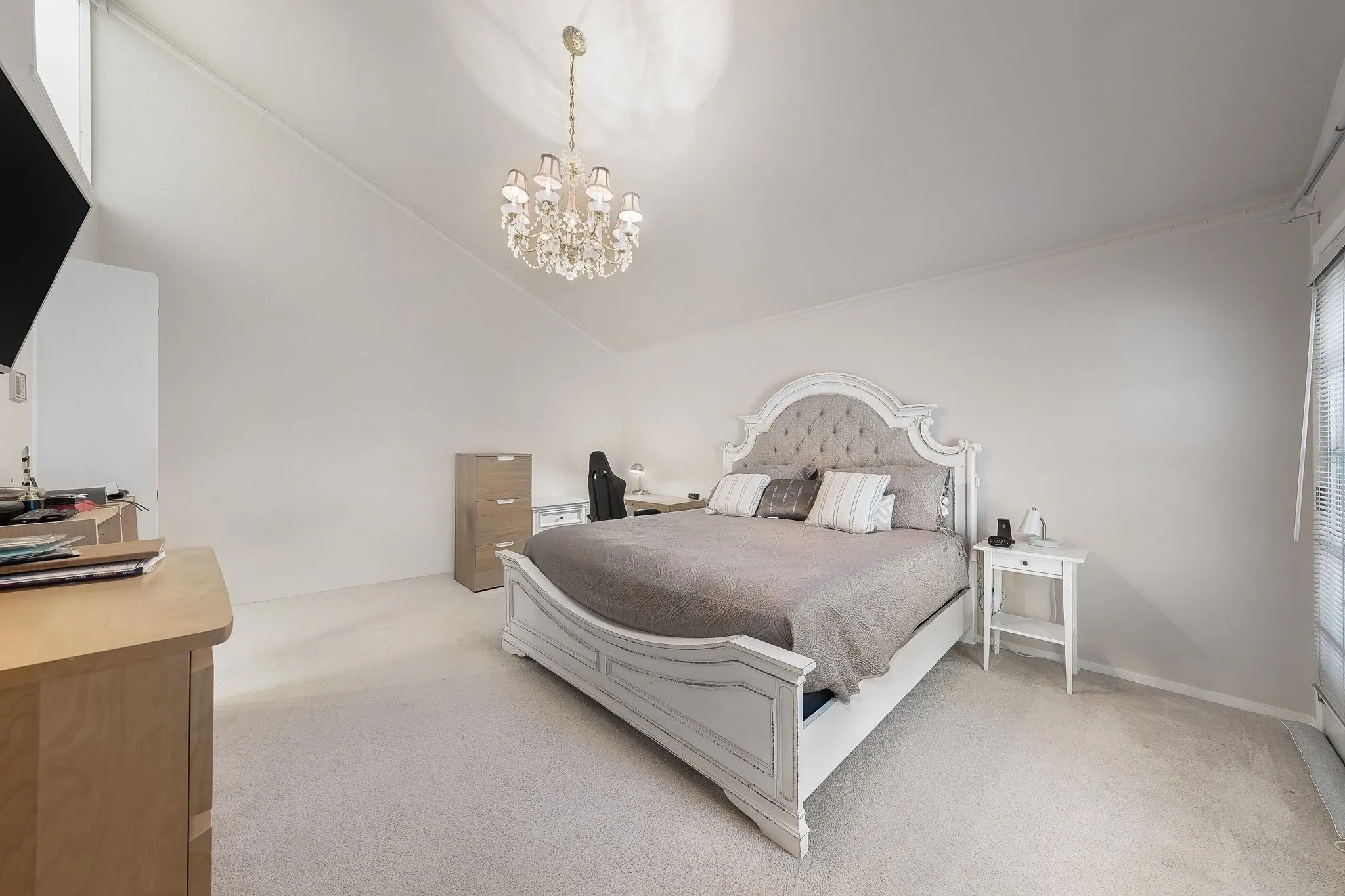 Spacious primary bedroom, vaulted ceilings, elegant chandelier, backyard door