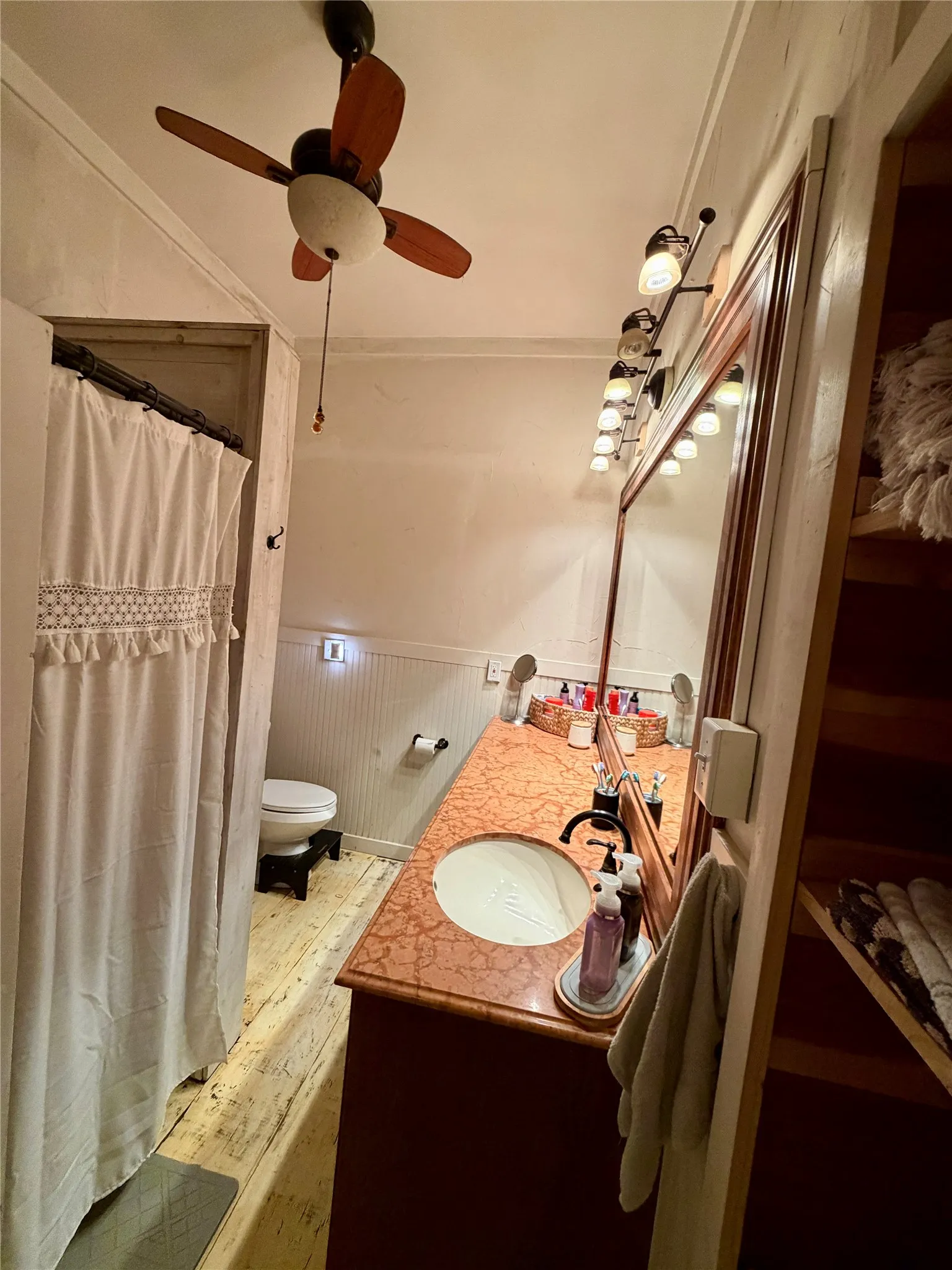 Bathroom featuring a wood-finish vanity with an integrated sink and a large mirror with track lighting