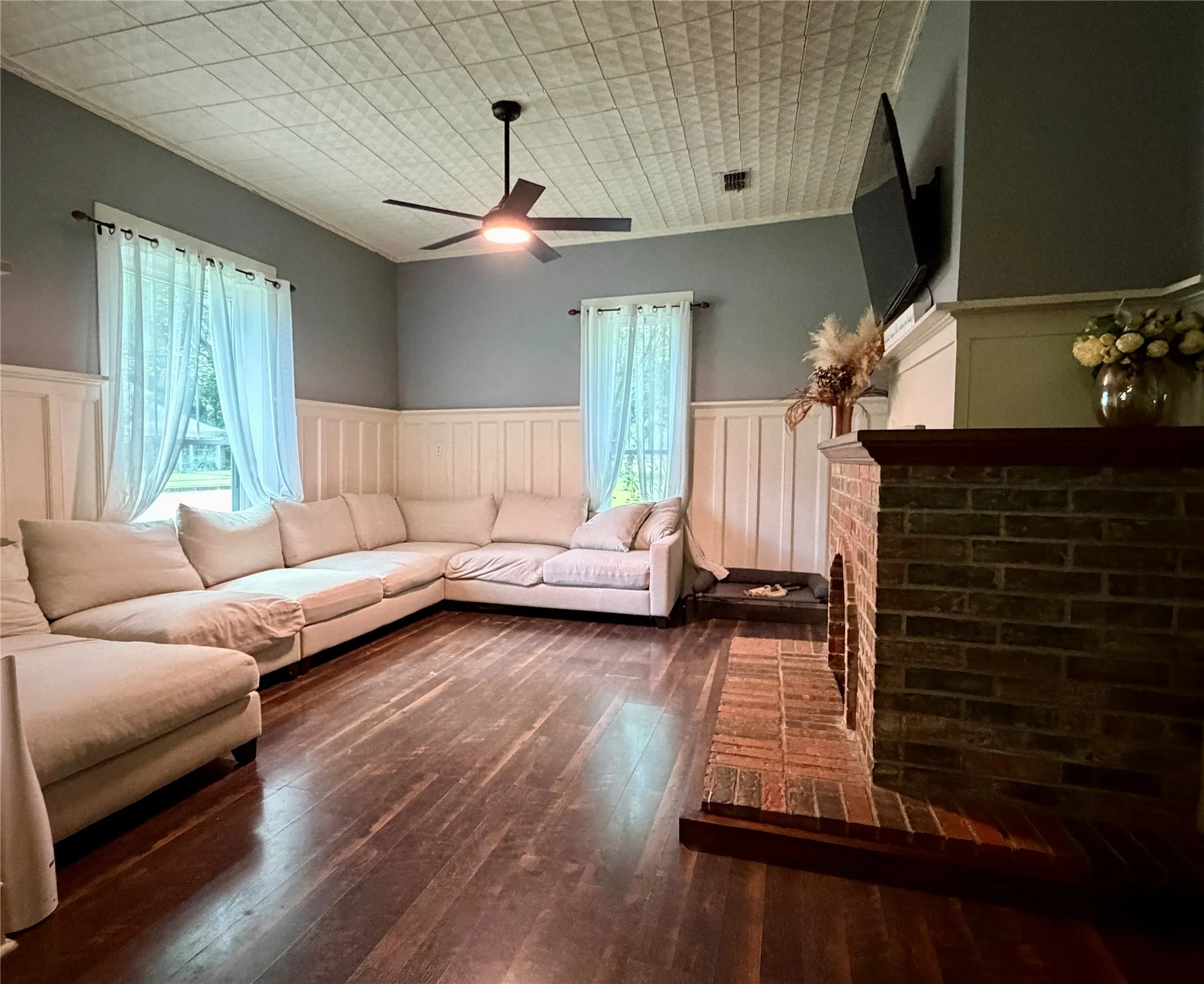 Living area featuring rich wood-finish flooring, textured ceiling, and a brick fireplace