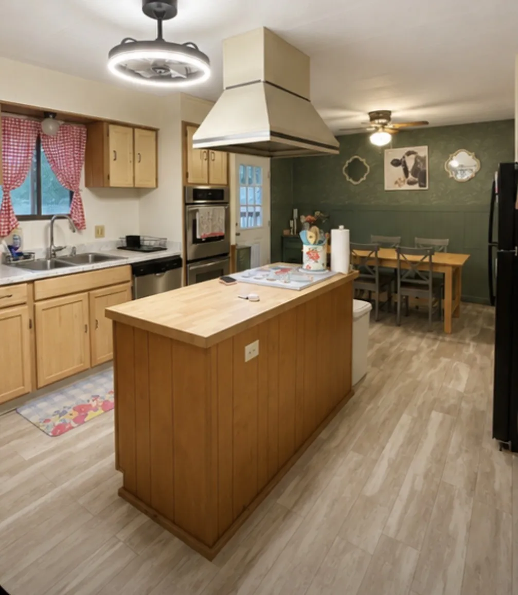 Hardwood flooring, wood cabinetry, stainless steel double oven, stainless steel dishwasher, and a center island with wood-finish countertop