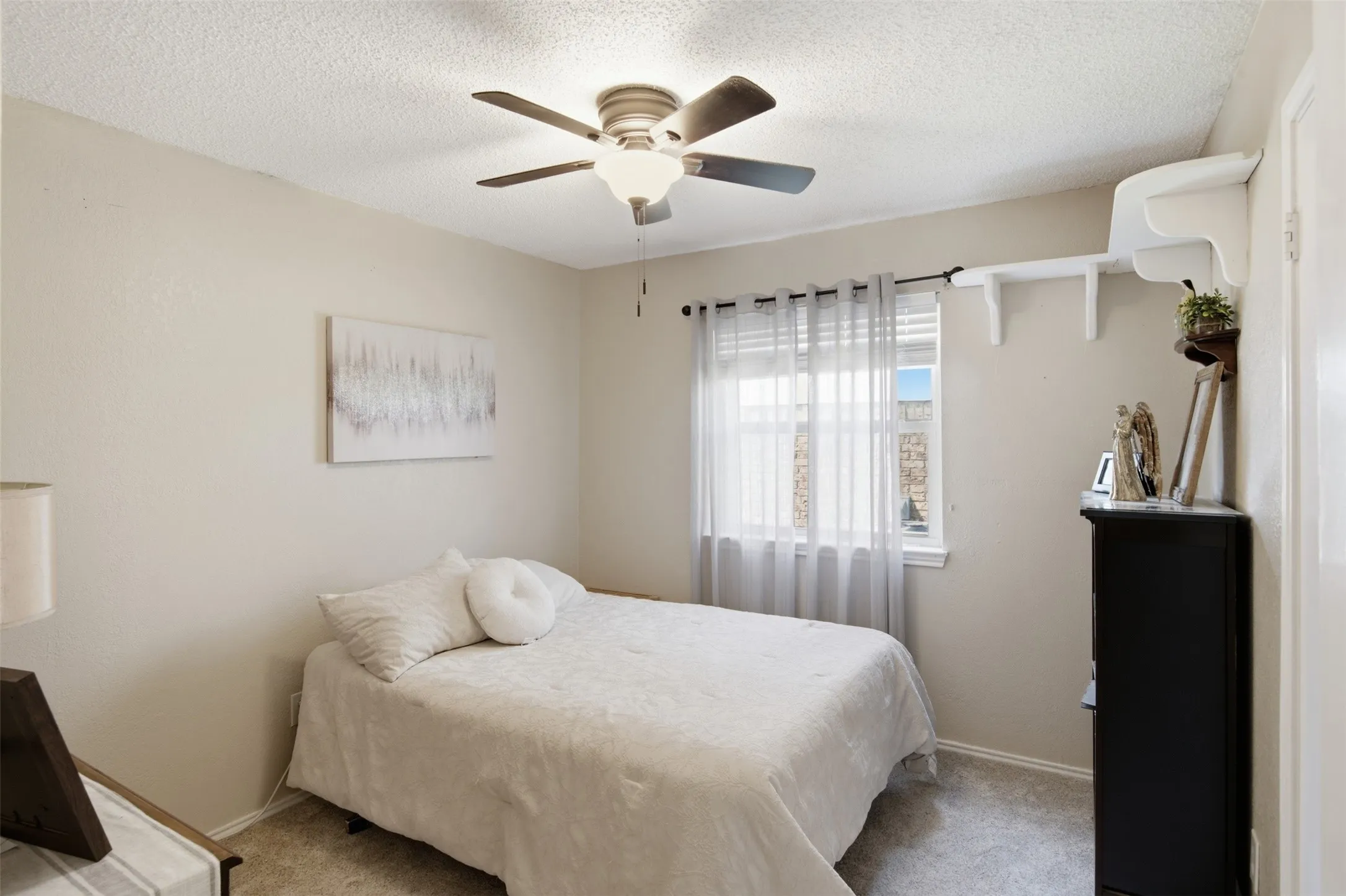 Room featuring a ceiling fan with integrated lighting, a window with sheer and blackout curtain rods, and neutral wall paint