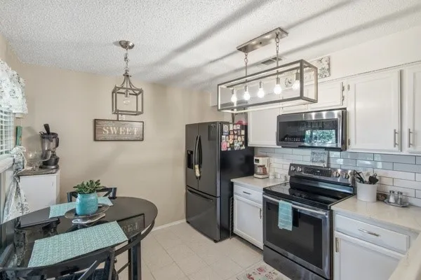Kitchen featuring white cabinetry with silver hardware, light countertops, and a subway tile backsplash