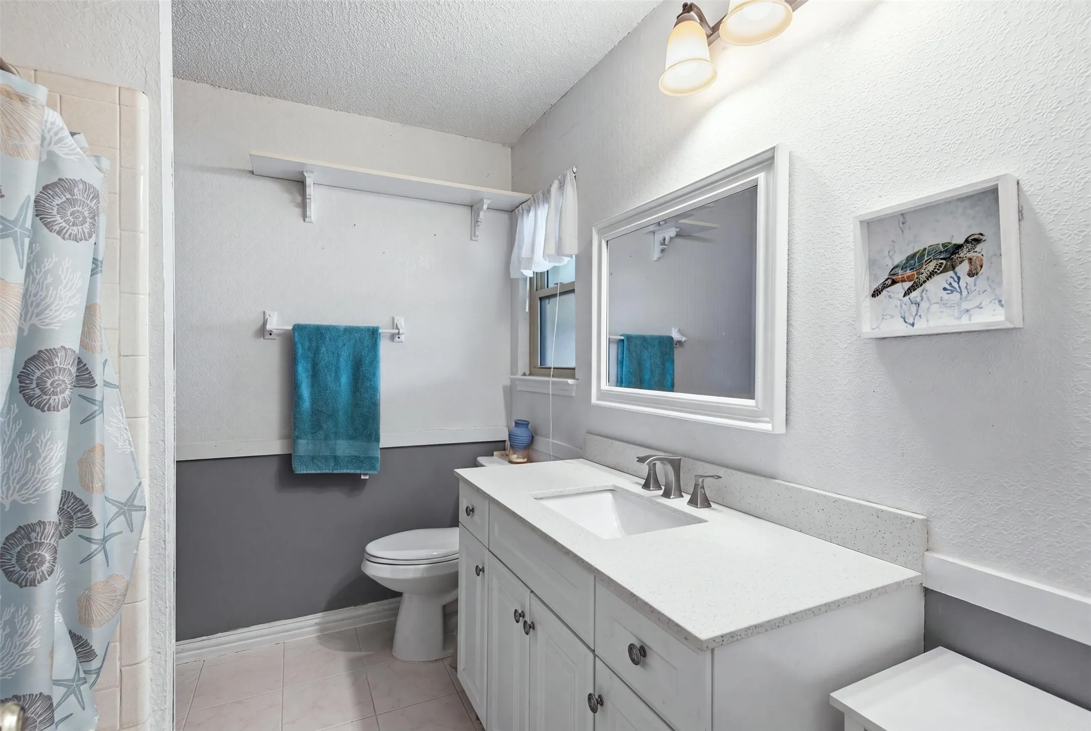 Bathroom featuring a white vanity with a light-toned countertop, a rectangular undermount sink, and a framed mirror