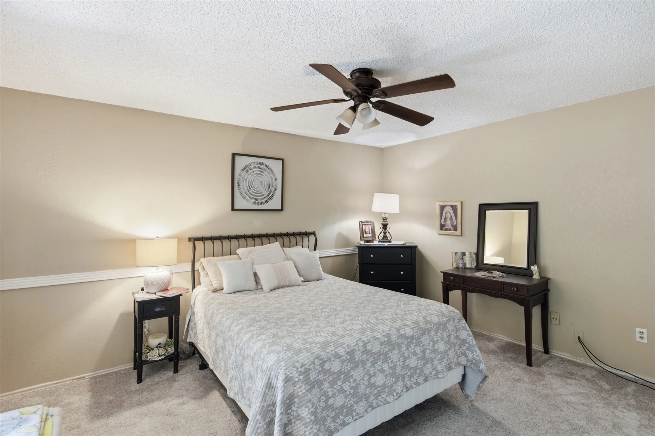 Neutral-toned room featuring a ceiling fan with integrated lighting, textured wall finish, and a white chair rail molding