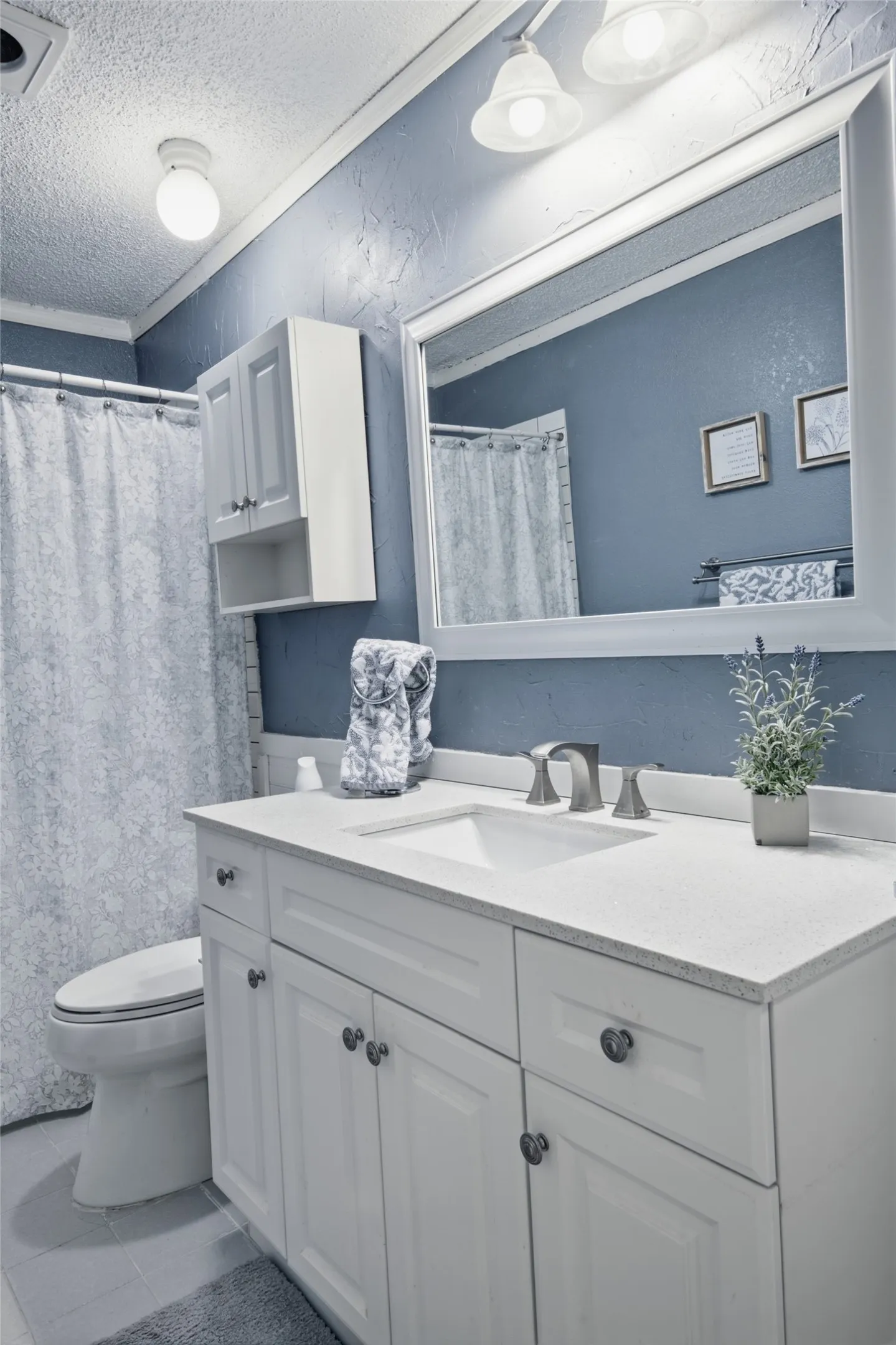 Bathroom featuring a white vanity with an integrated sink, brushed nickel faucet, and a light-toned countertop