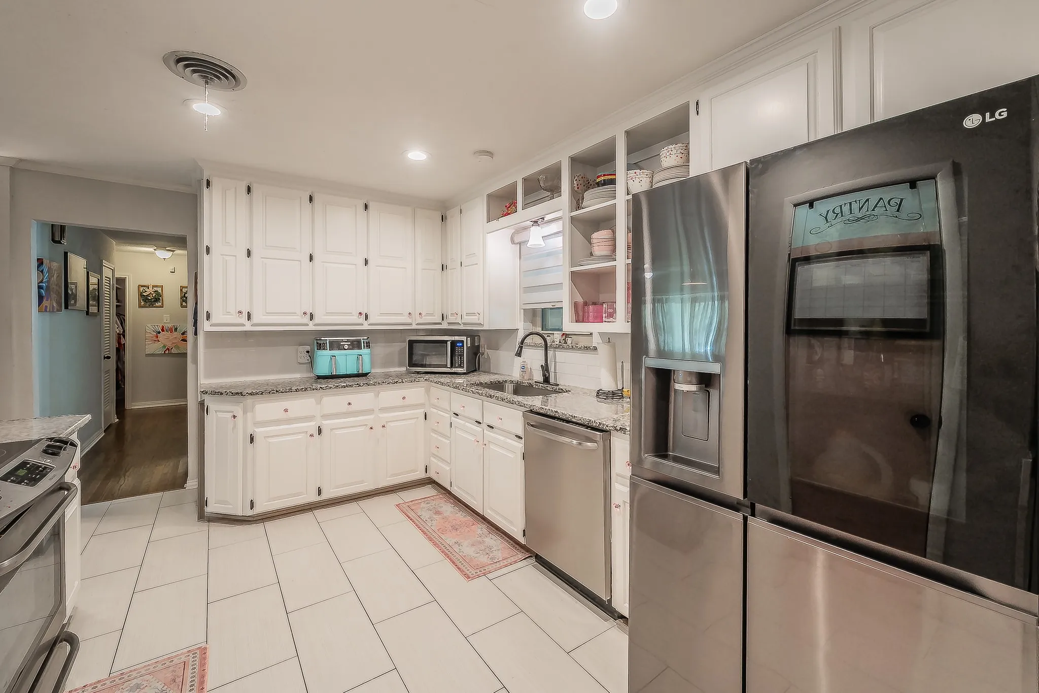 Kitchen featuring white cabinetry, light-toned tile flooring, and granite-style countertops