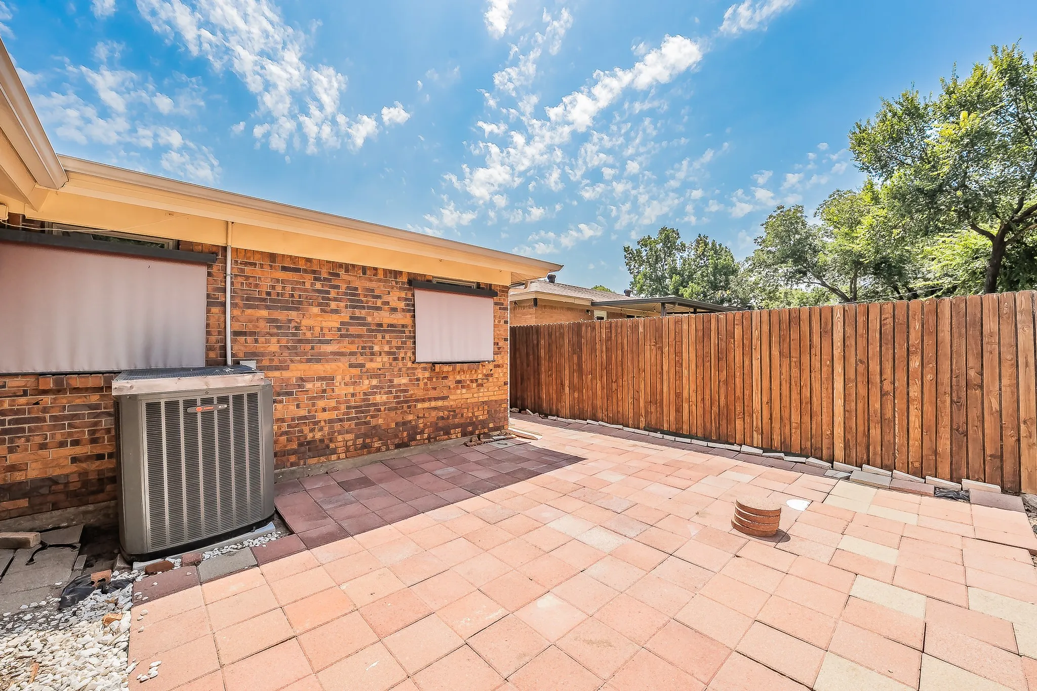 Side yard in back, Patio area featuring red brick paver flooring, a new wood fence, and a brick exterior facade